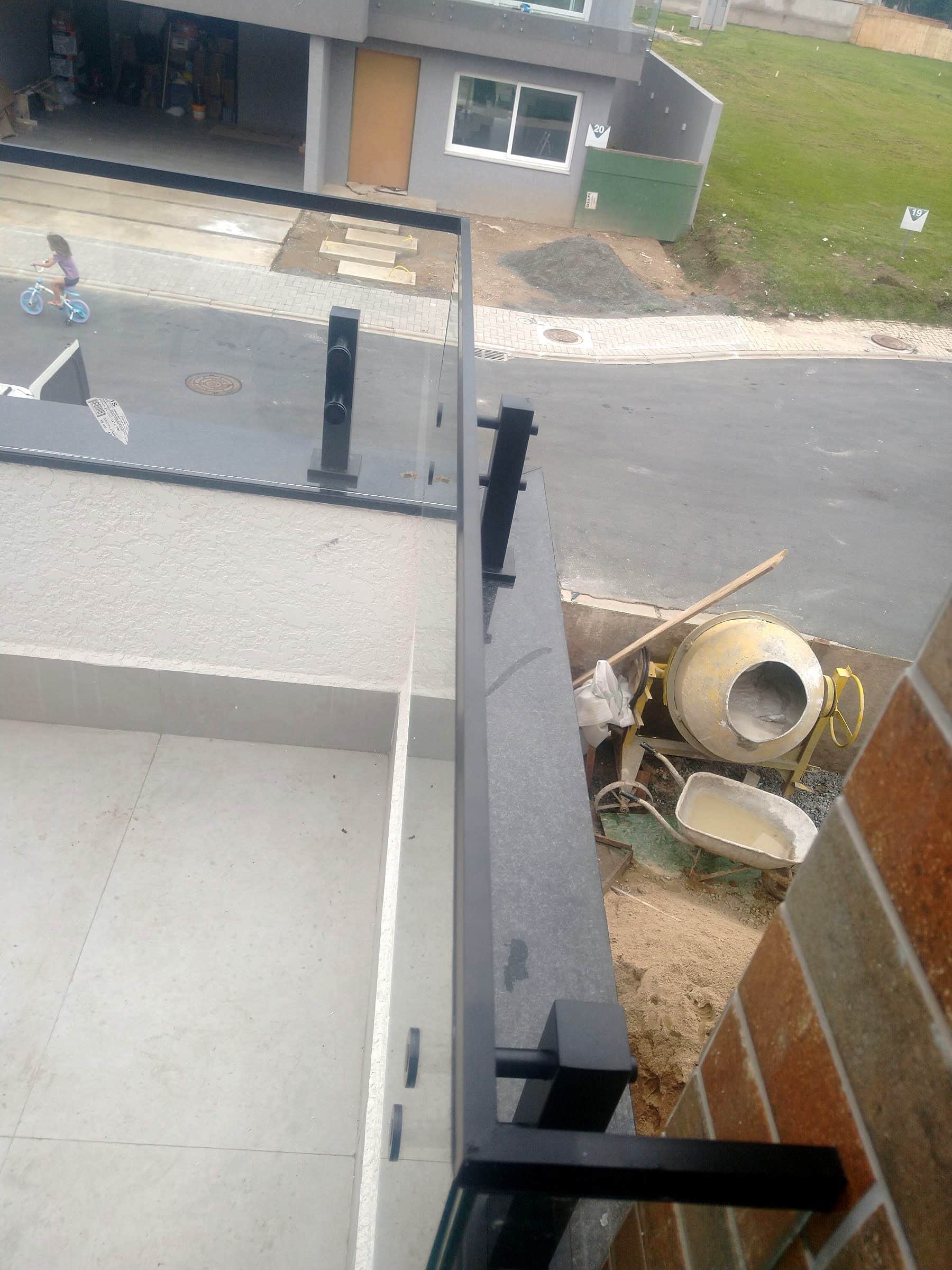 Fixações laterais instaladas na borda da laje antes do vidro, em obra em andamento