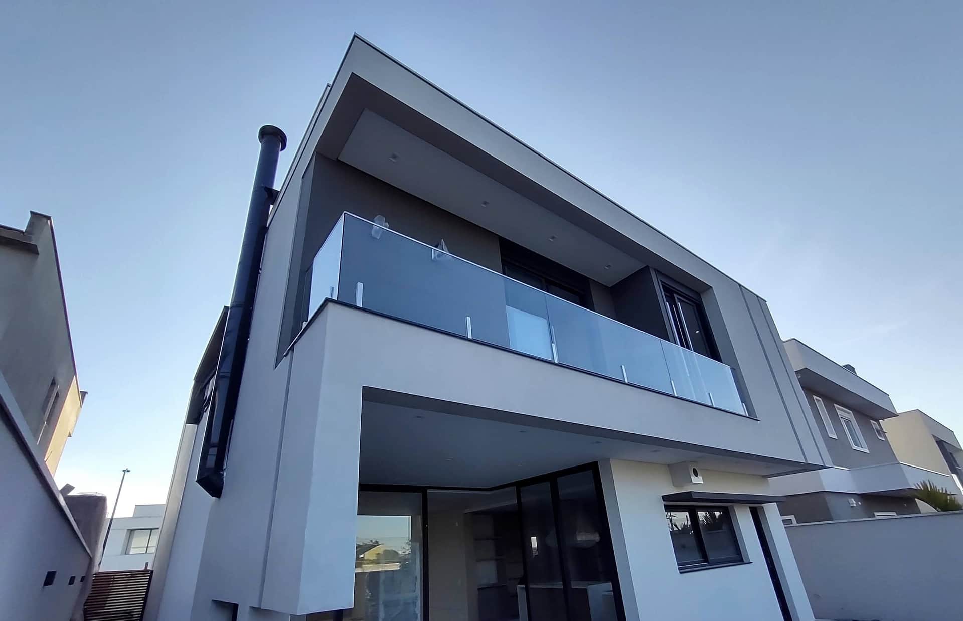 Fachada com sacada em vidro e colunas em inox sob céu azul