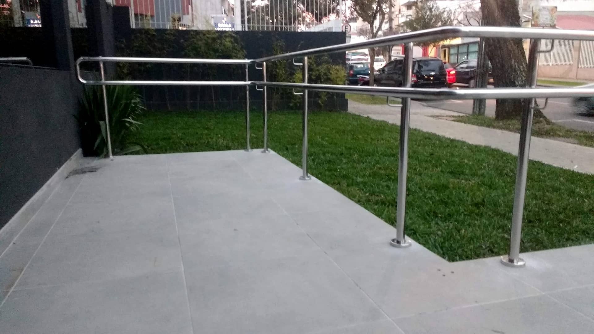 Patamar da rampa com o corrimão em inox contornando o jardim