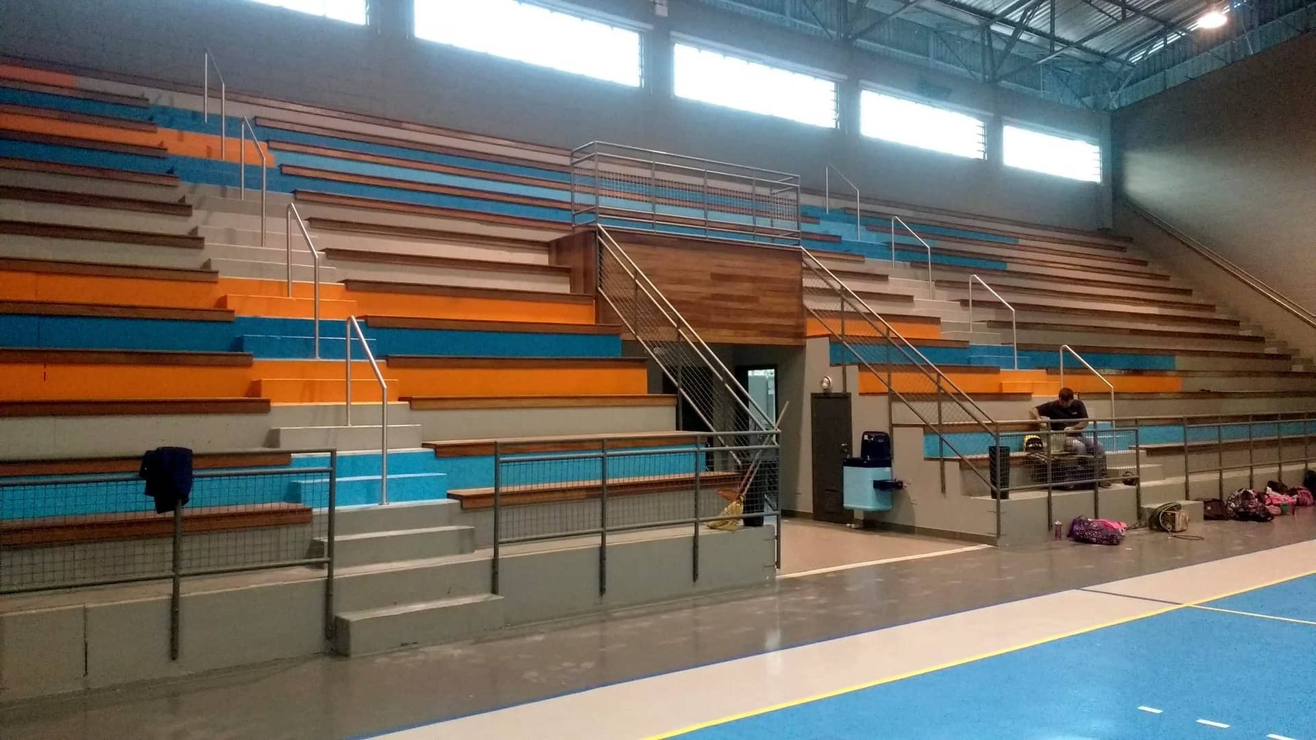 Arquibancada de ginásio com corrimãos centrais em inox nas escadas
