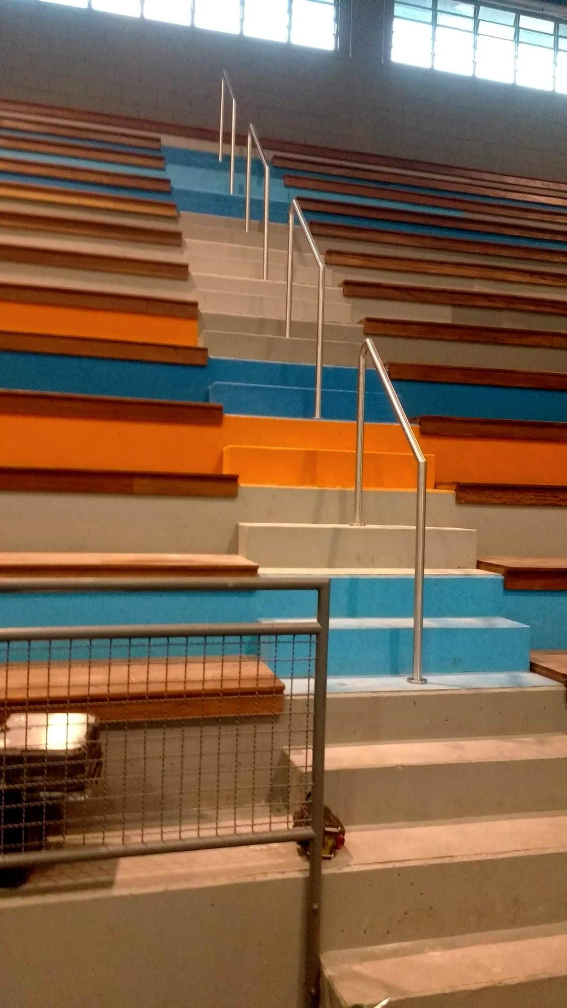 Corrimão central em inox subindo a escada da arquibancada