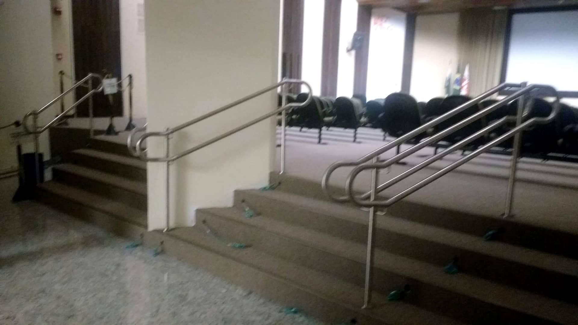 Escadas laterais do auditório com corrimão duplo em inox