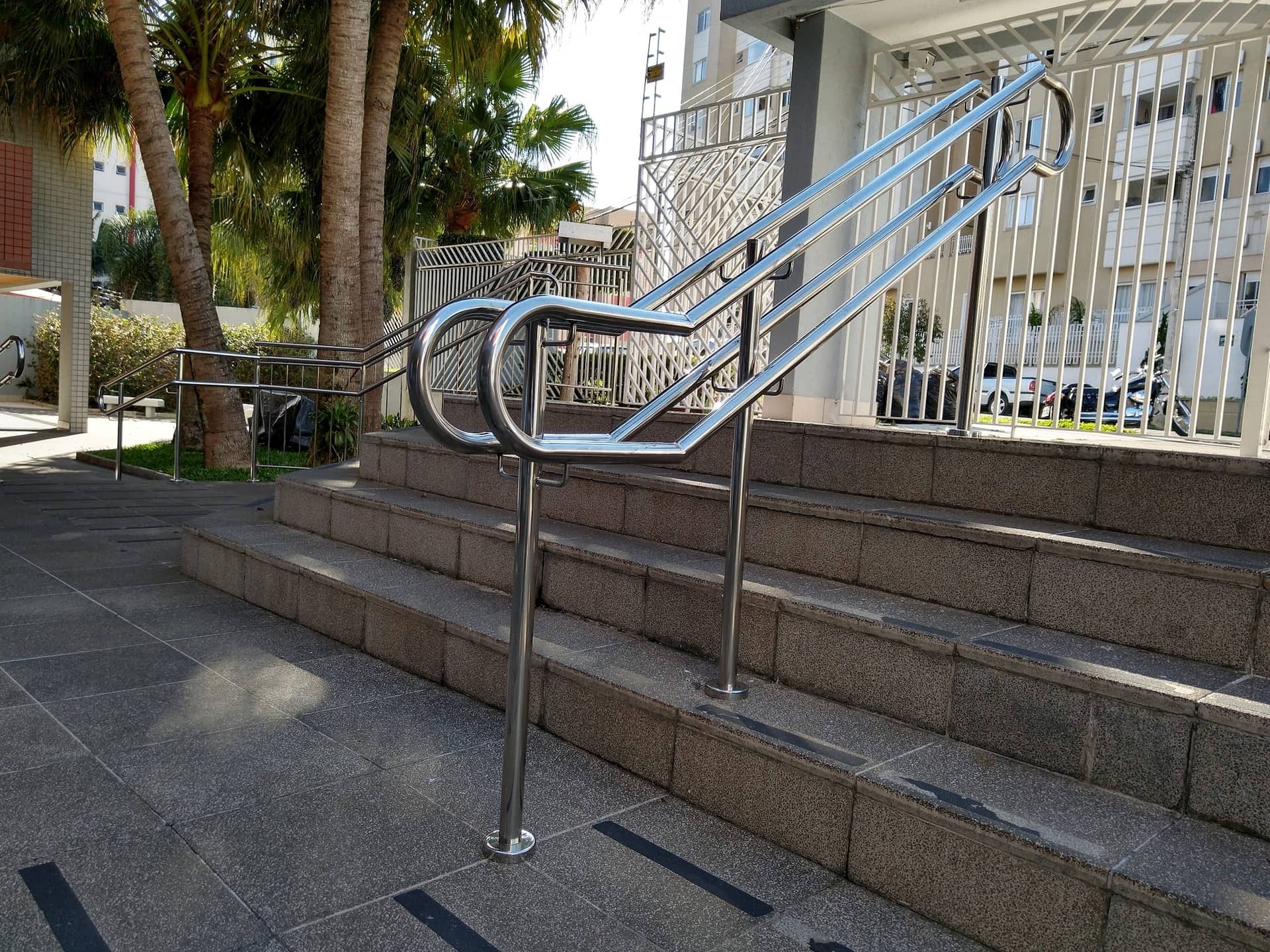 Pontas curvas do corrimão duplo em inox no pé da escada