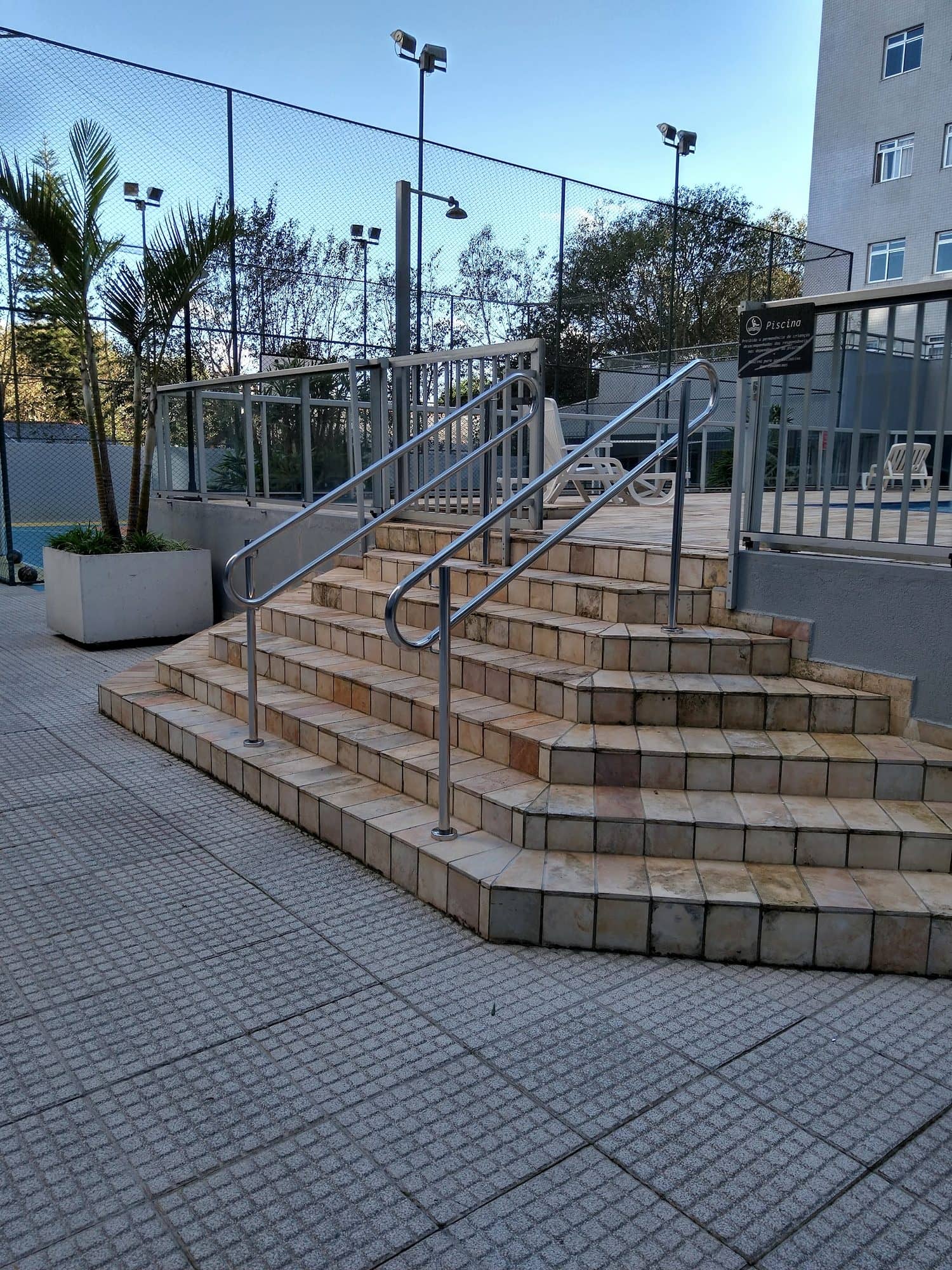 Escadaria externa do condomínio com corrimãos em inox