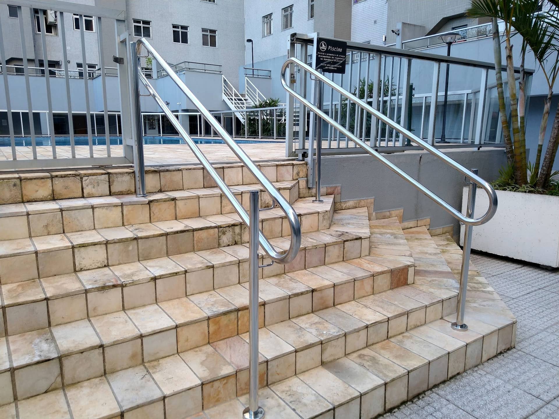 Corrimãos duplos em inox na escadaria junto à piscina do condomínio