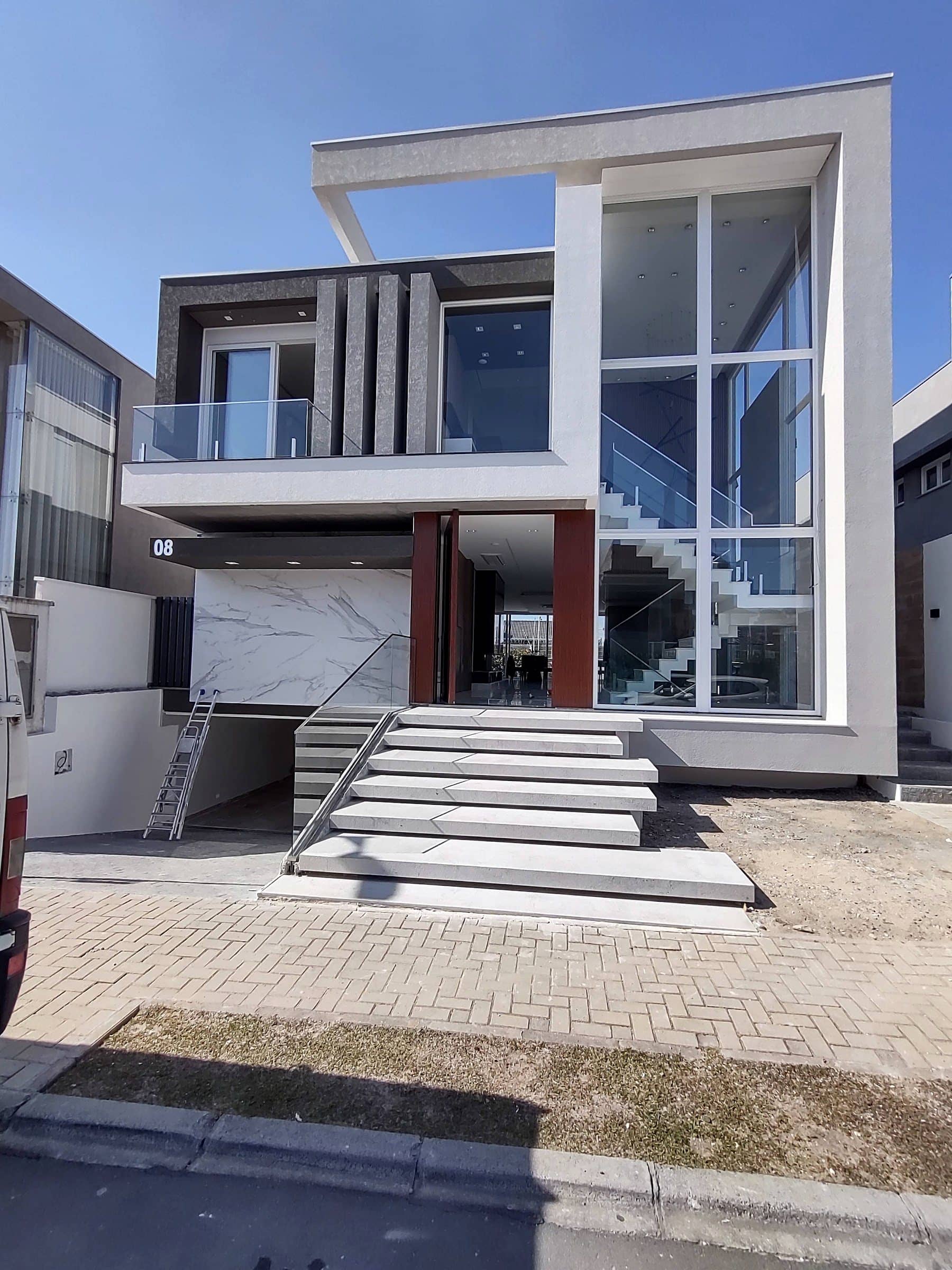 Fachada de casa contemporânea com escadaria de entrada e guarda-corpo de vidro