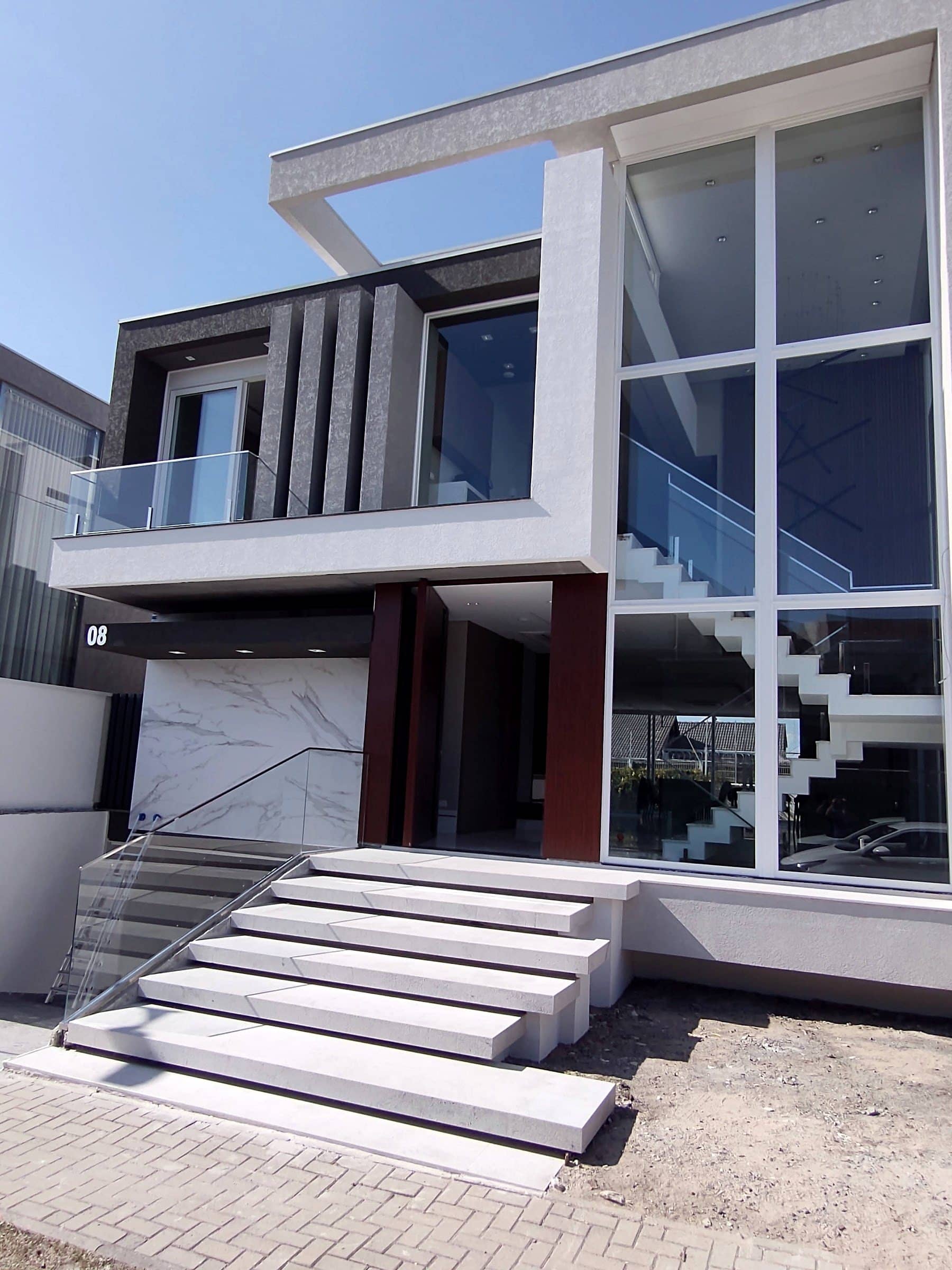 Acesso da casa com escadaria e guarda-corpo de vidro