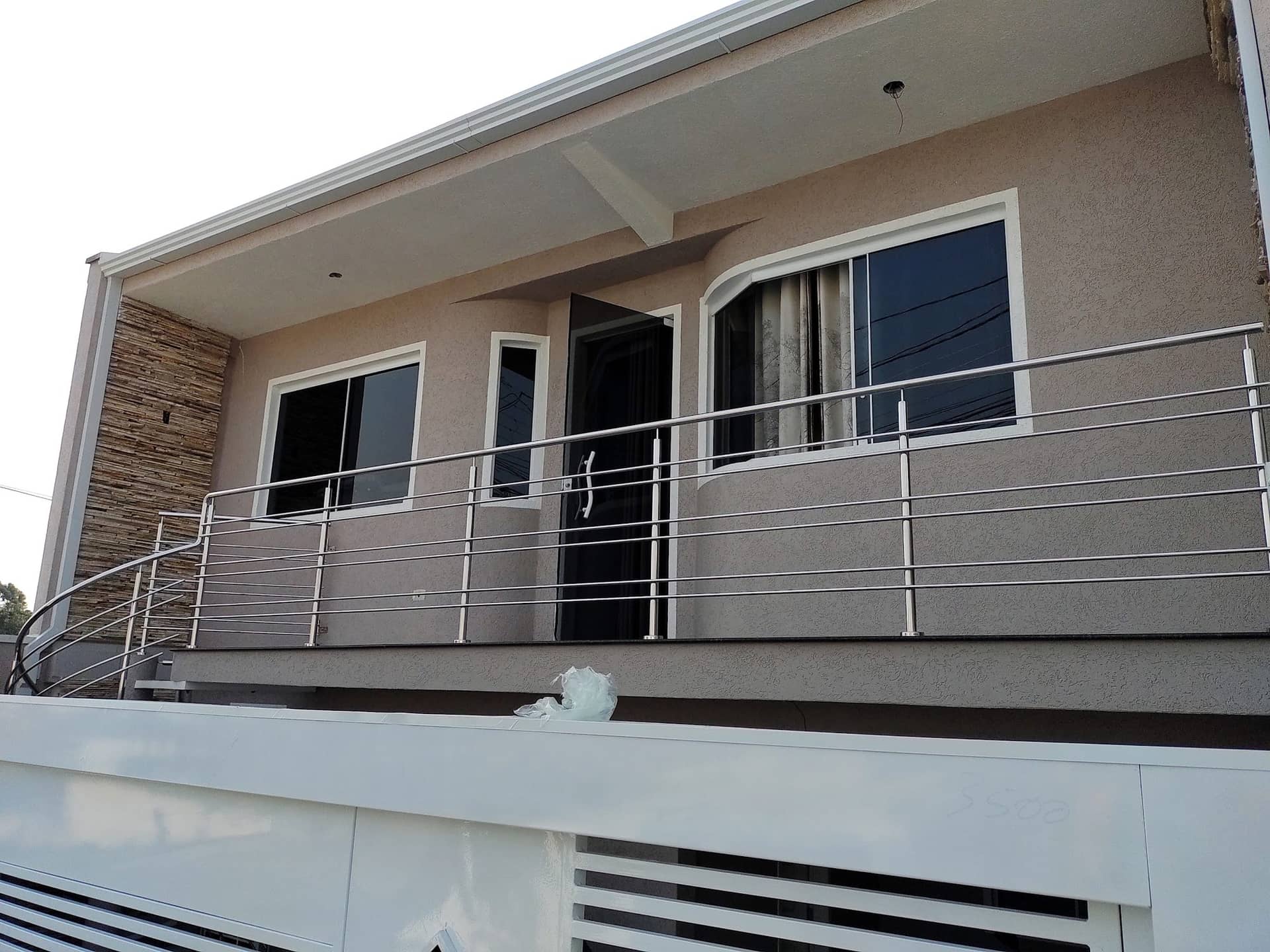 Sacada frontal da casa com guarda-corpo de hastes horizontais em inox