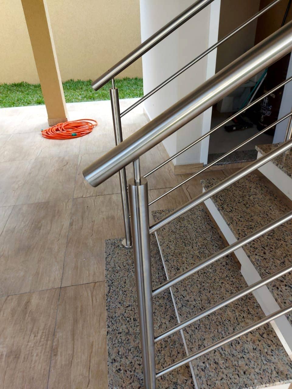 Corrimão tubular em inox com ponta arredondada no início da escada