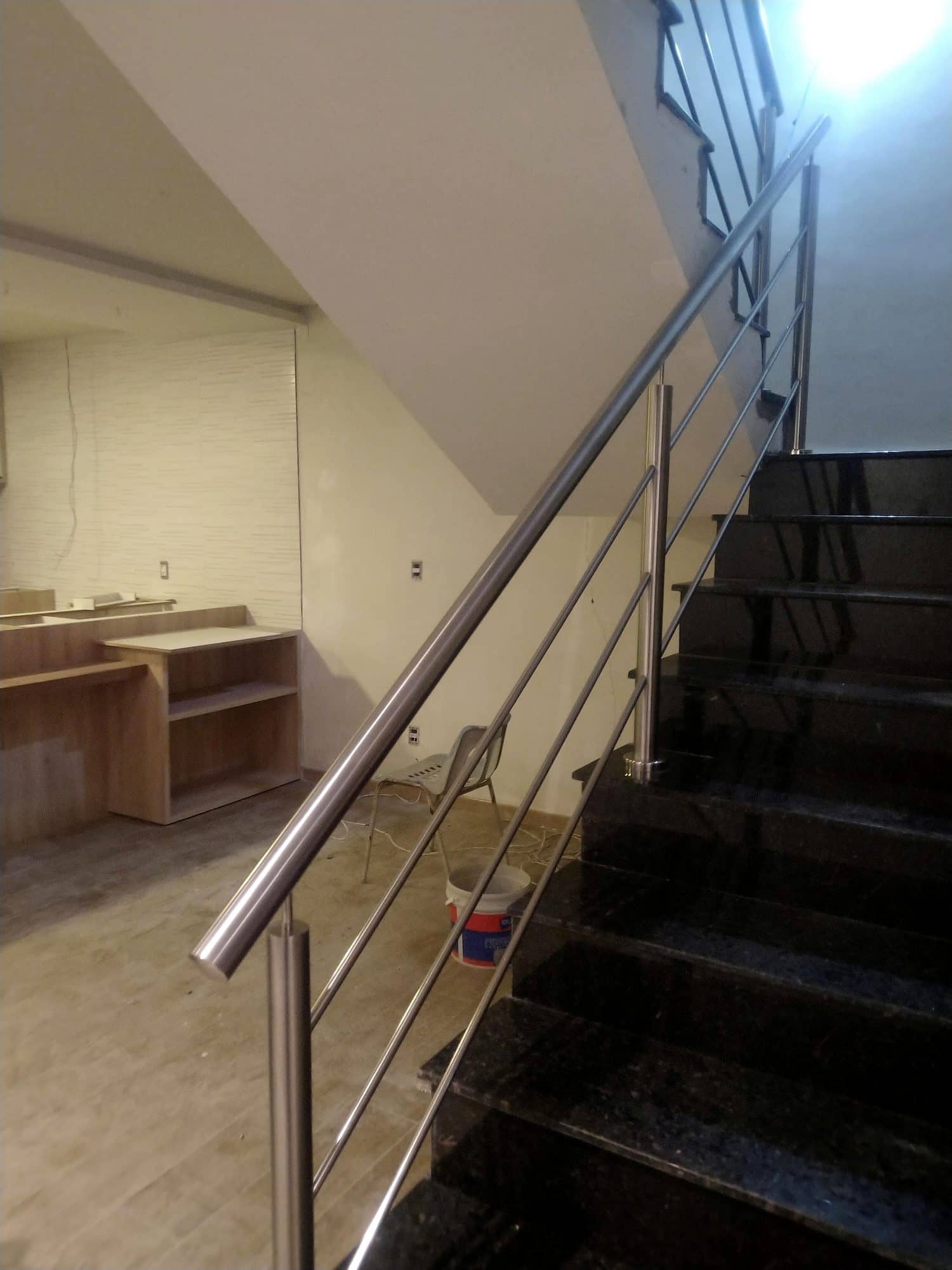 Escada em granito preto com corrimão e hastes horizontais em inox