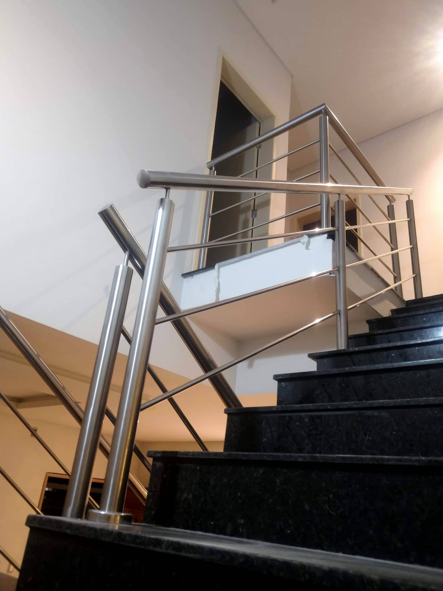 Patamar da escada com o corrimão em inox fazendo a volta para o lance seguinte