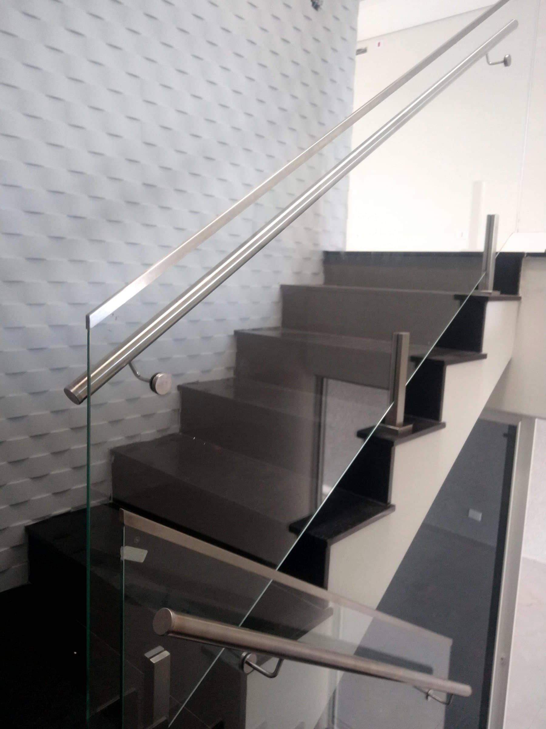 Corrimão em inox acompanhando a escada com guarda-corpo de vidro