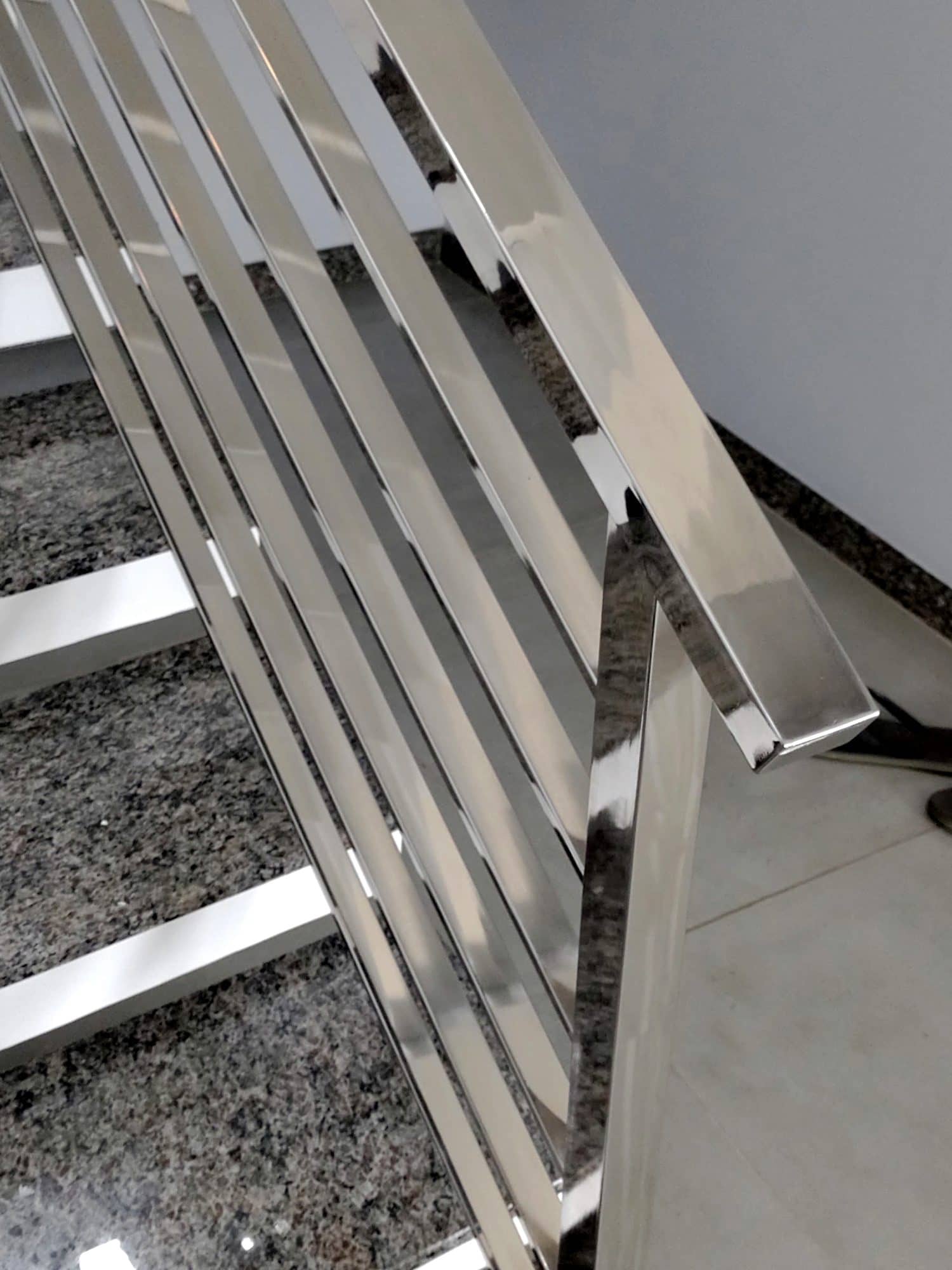 Detalhe do corrimão quadrado em inox polido sobre as hastes inclinadas