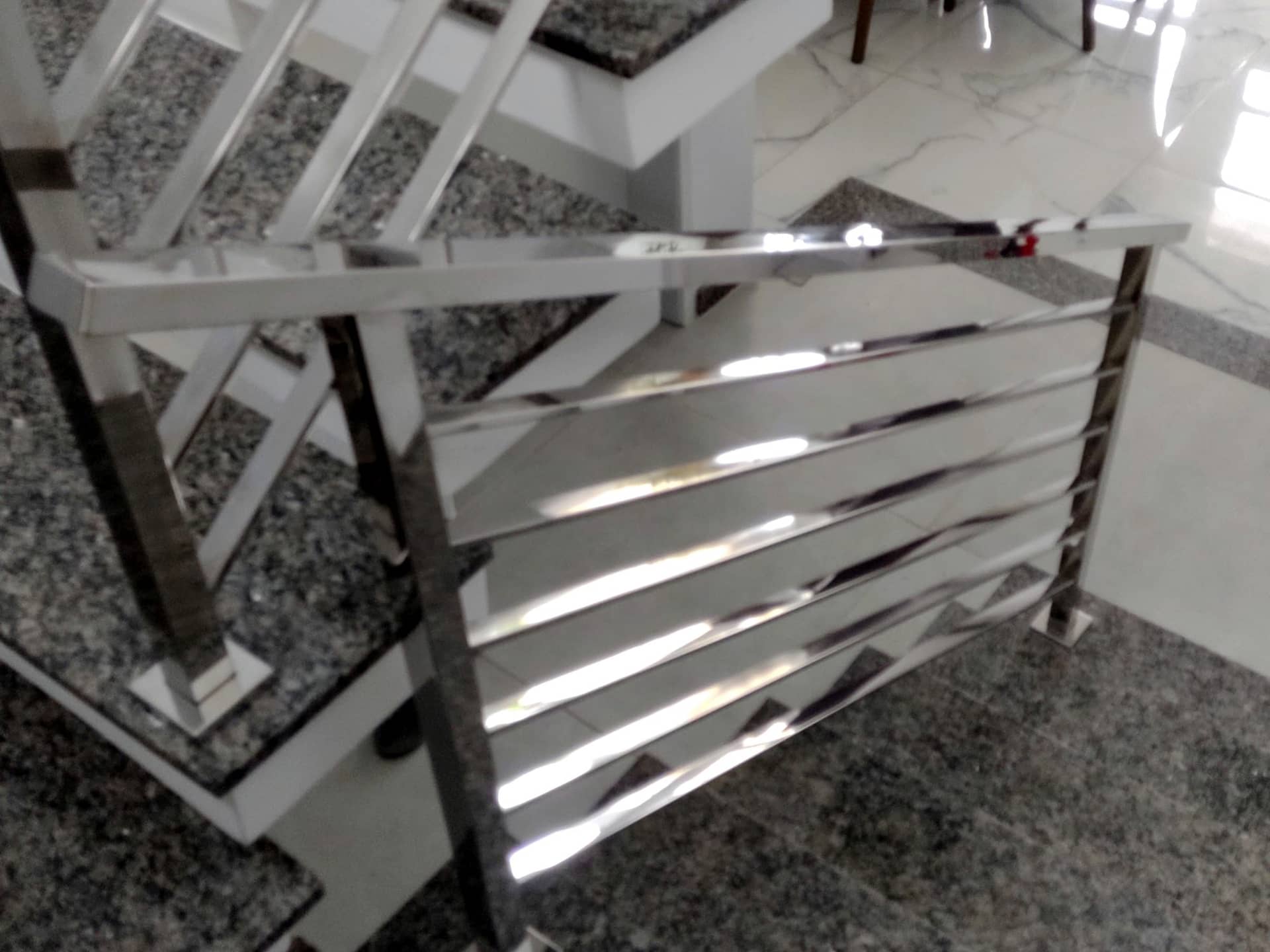 Detalhe da base do guarda-corpo em tubo quadrado polido fixada no degrau de granito