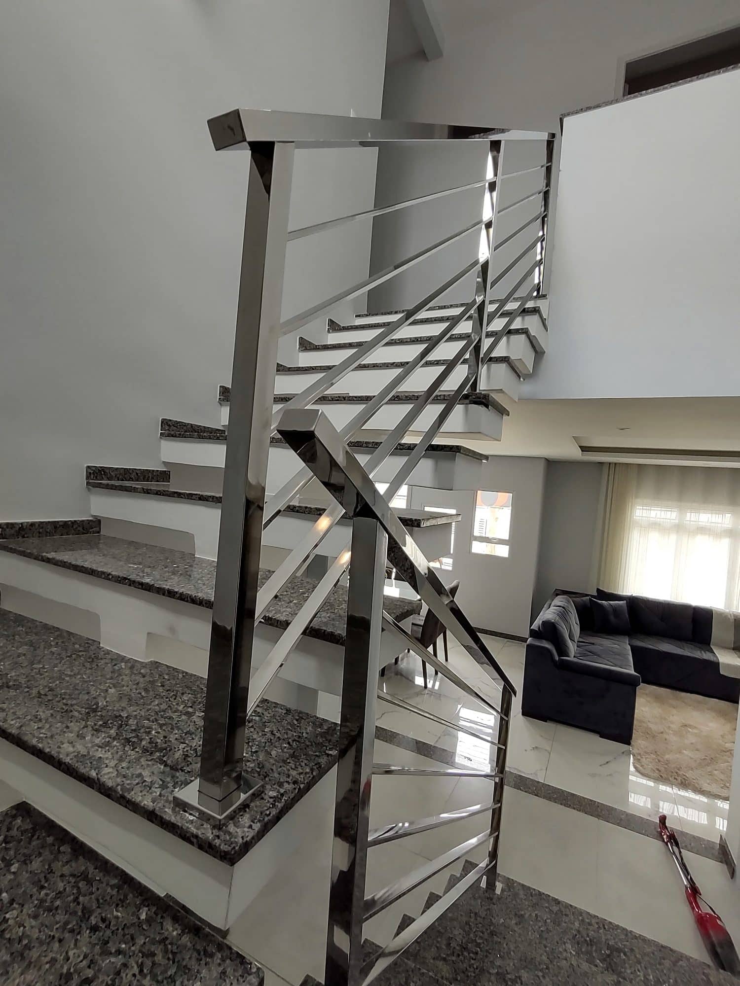 Coluna quadrada em inox polido no início do lance superior da escada
