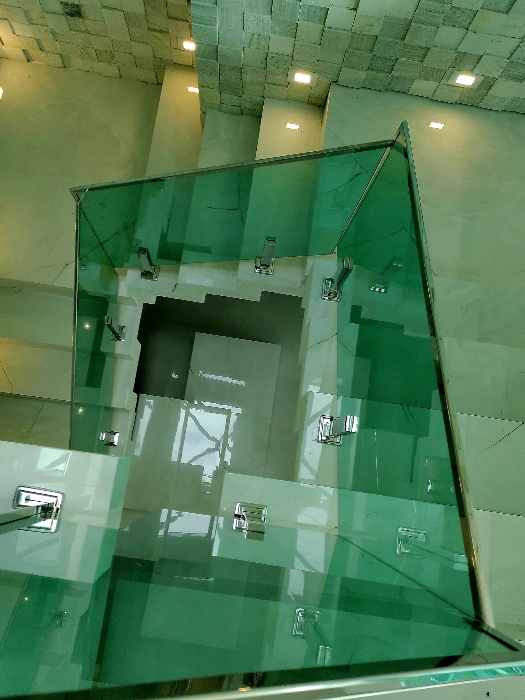 Poço da escada visto de cima através do vidro verde, com fixações em inox