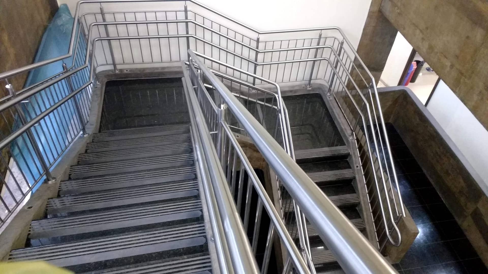 Escadaria com guarda-corpo de travessas verticais em inox nos dois lados do lance