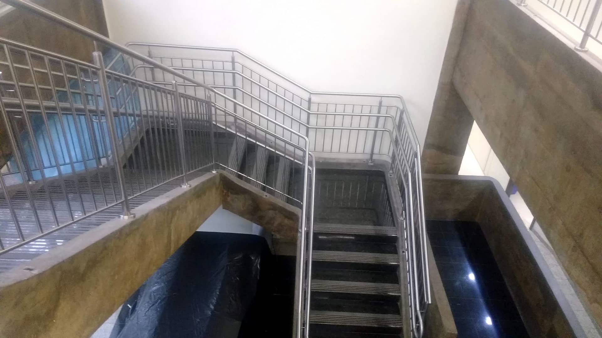 Escadaria vista do alto, com guarda-corpo de travessas verticais em inox