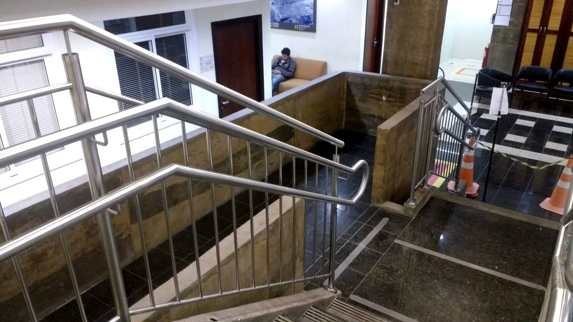 Corrimão em inox acompanhando o lance da escadaria junto à janela