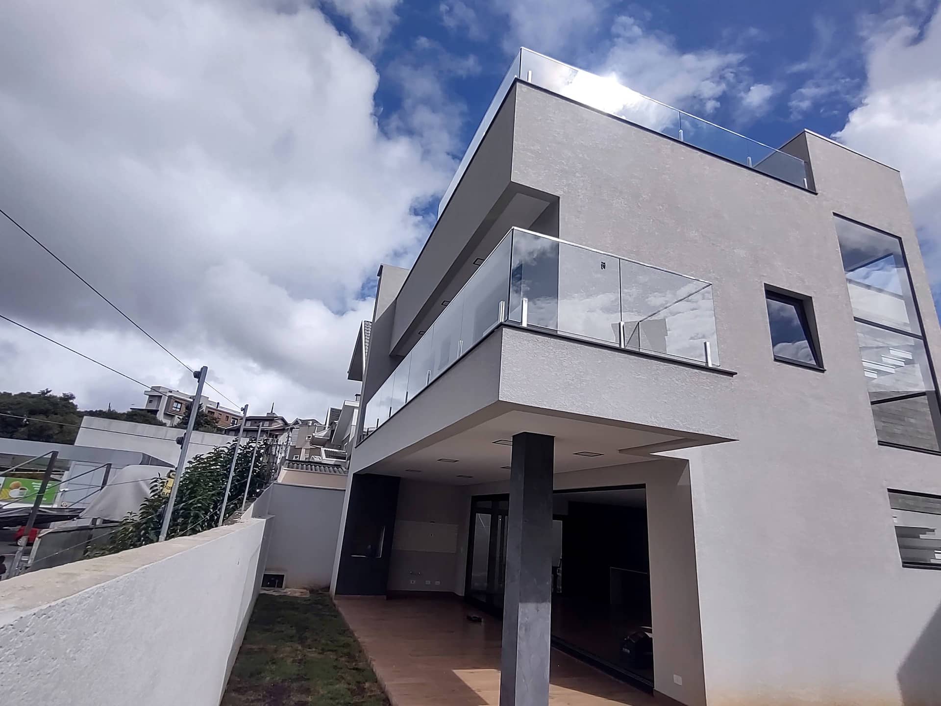 Fachada com sacadas em balanço e guarda-corpo de vidro sob céu azul