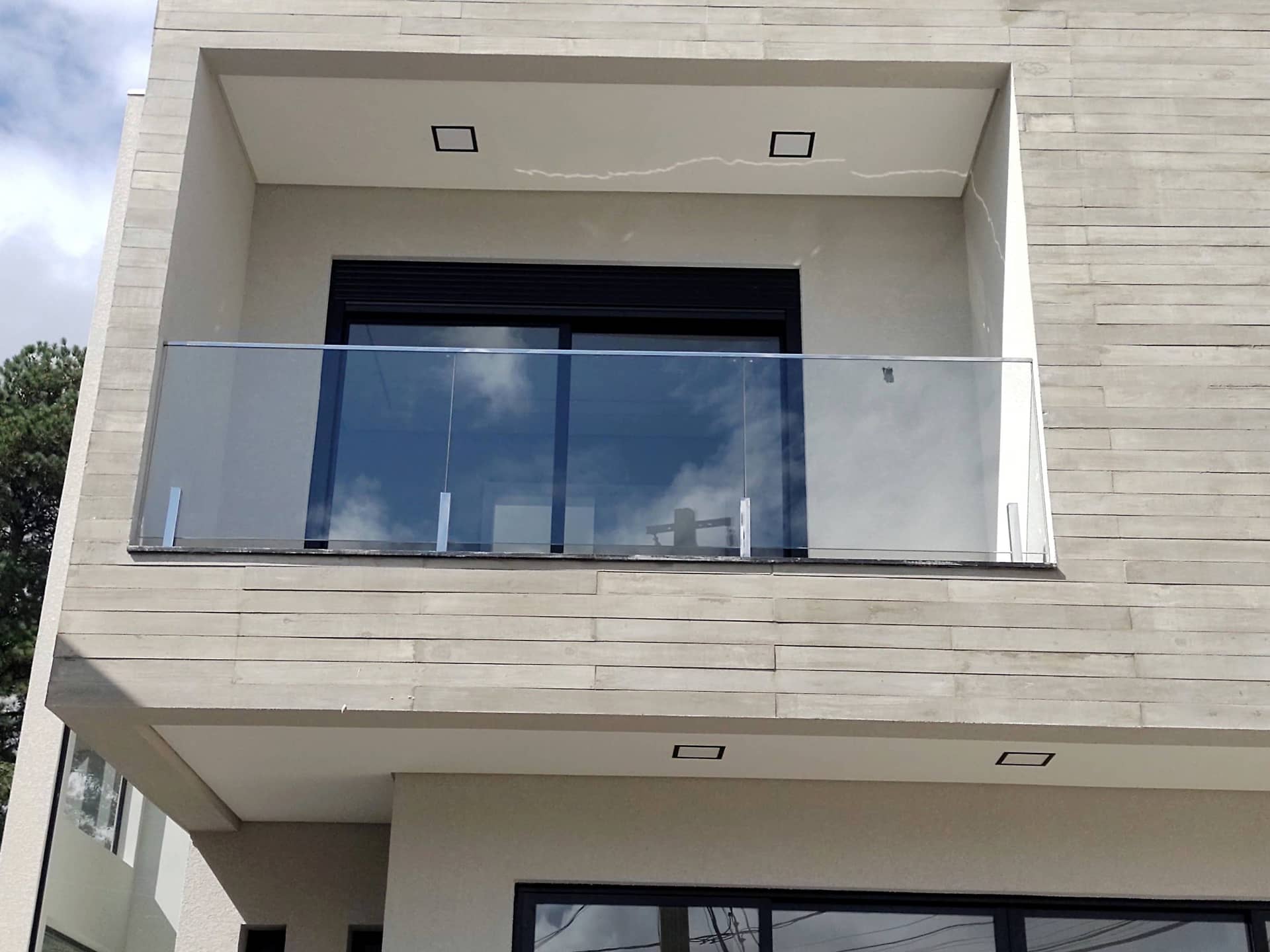 Sacada com guarda-corpo de vidro em fachada revestida