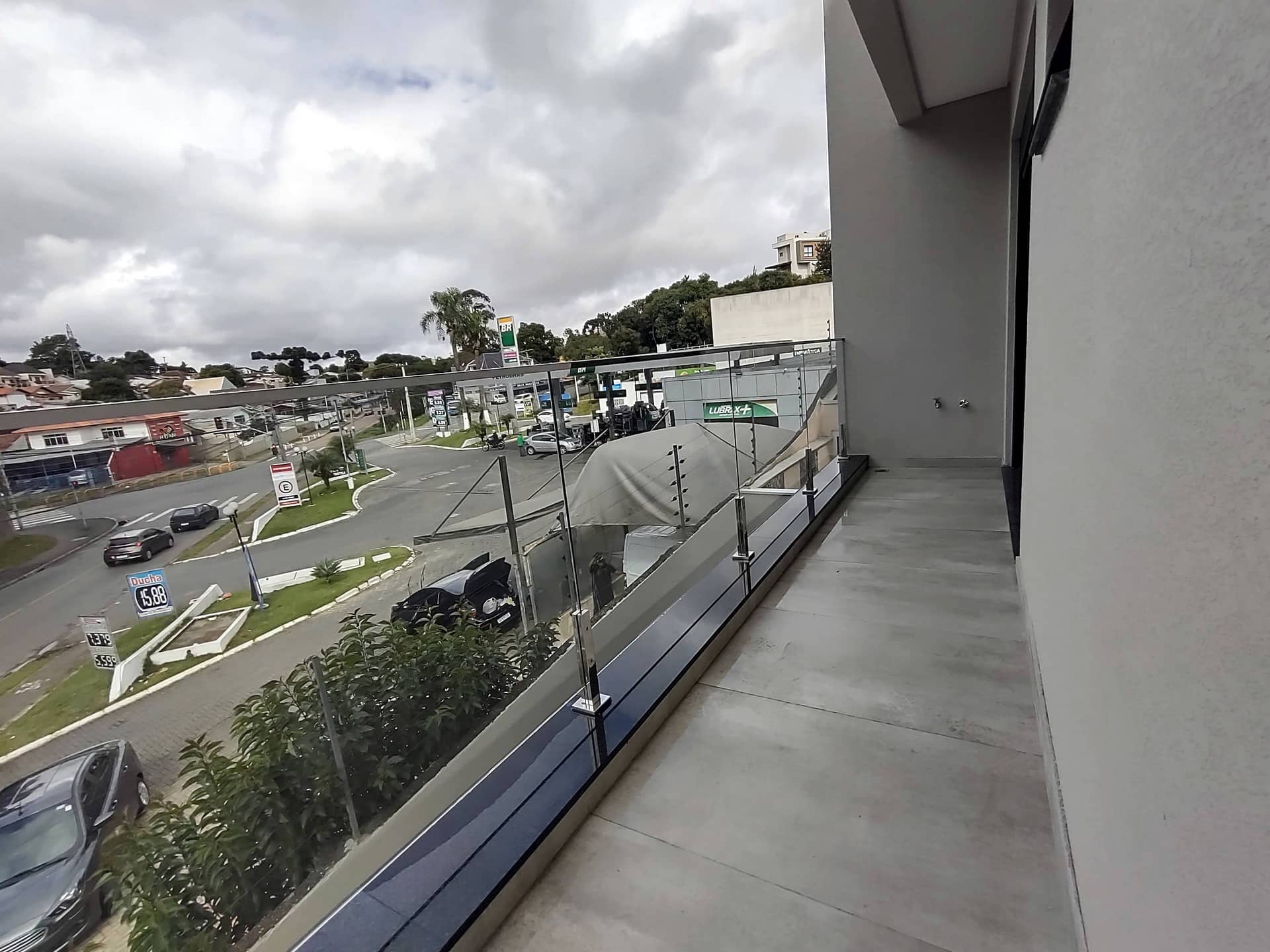 Varanda com guarda-corpo de vidro e vista para avenida