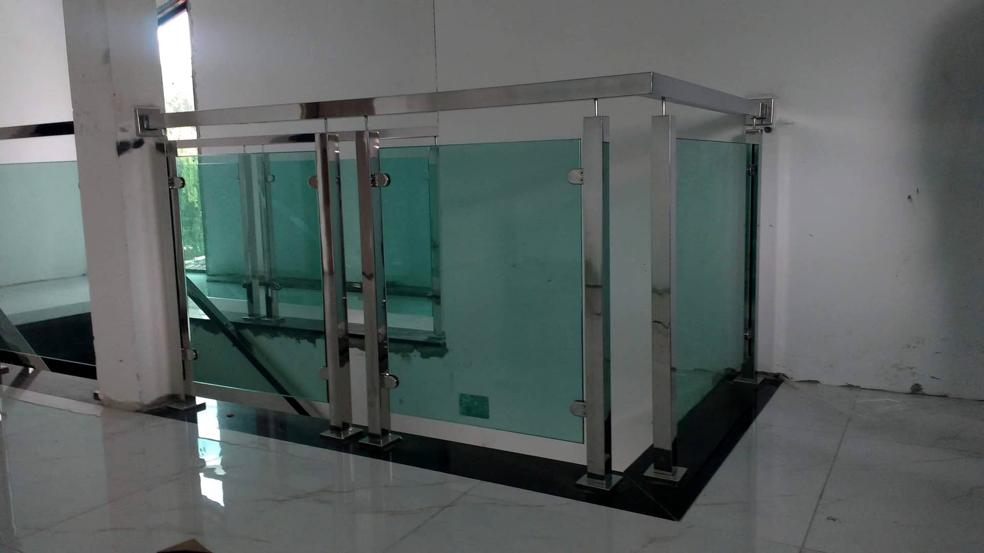 Fechamento de vão de escada com estrutura tubular em inox e vidro verde