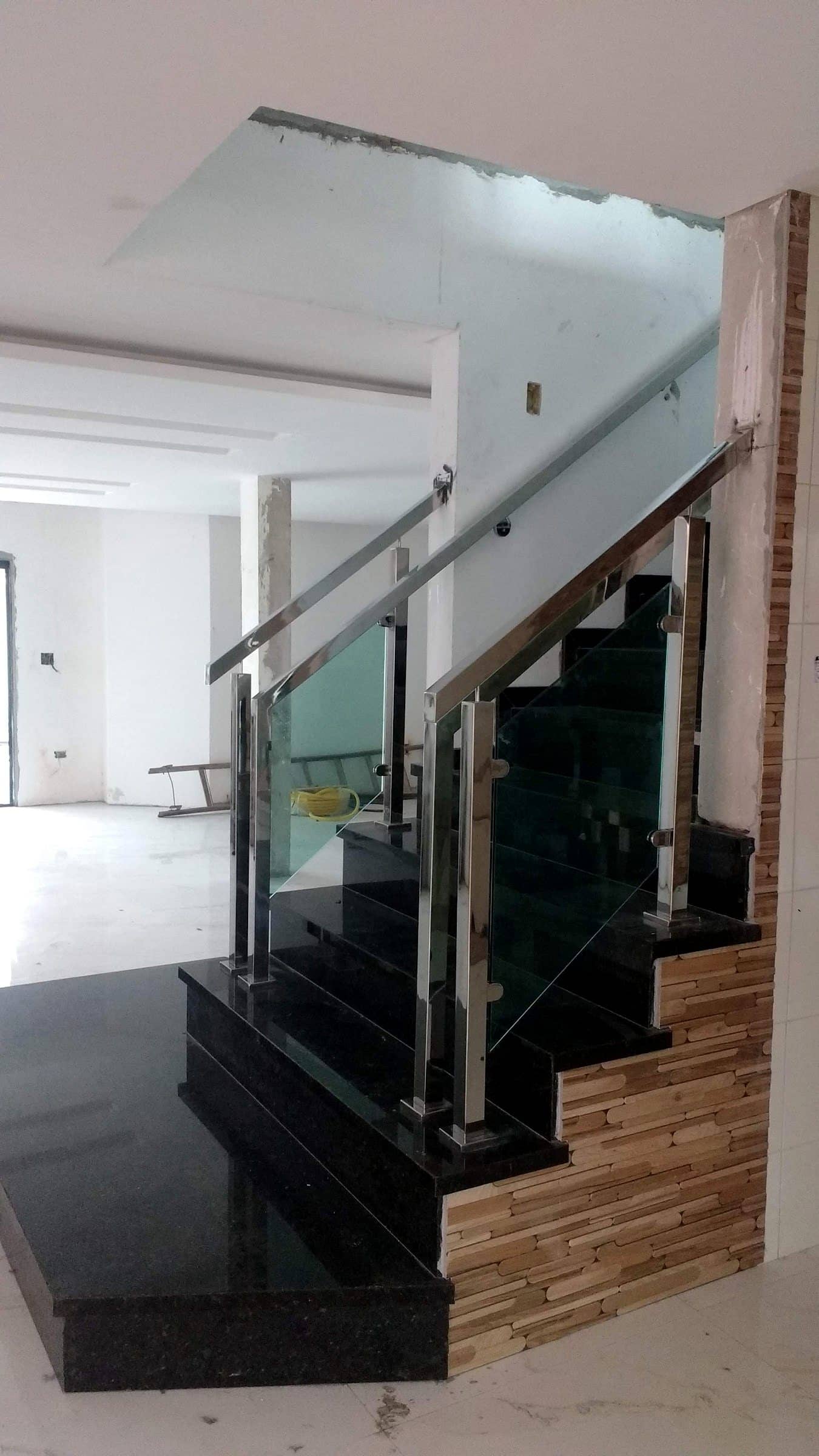 Escada em granito com guarda-corpo de vidro e corrimão em inox