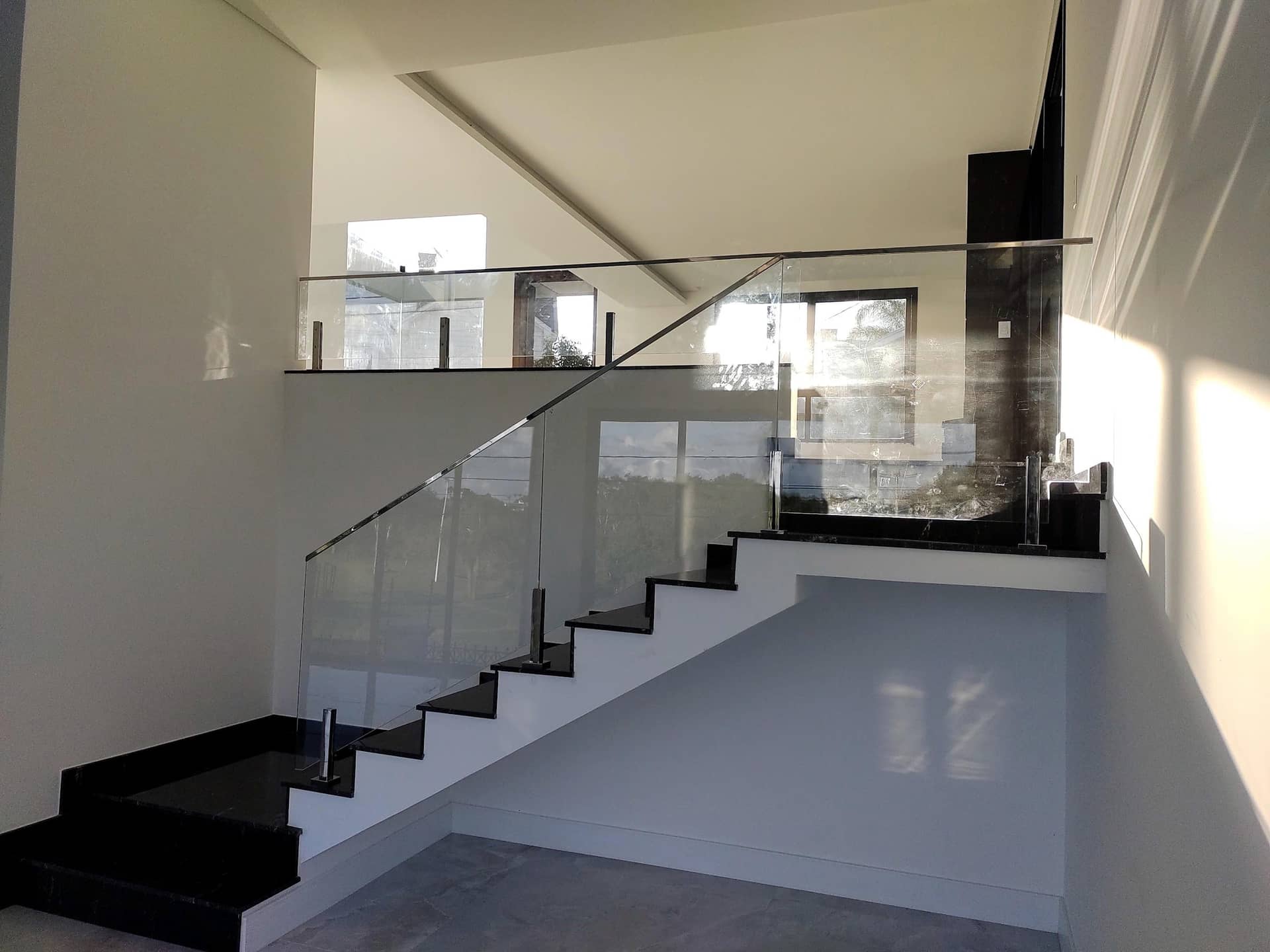 Escada e mezanino com vidro e colunas em inox, com luz natural lateral