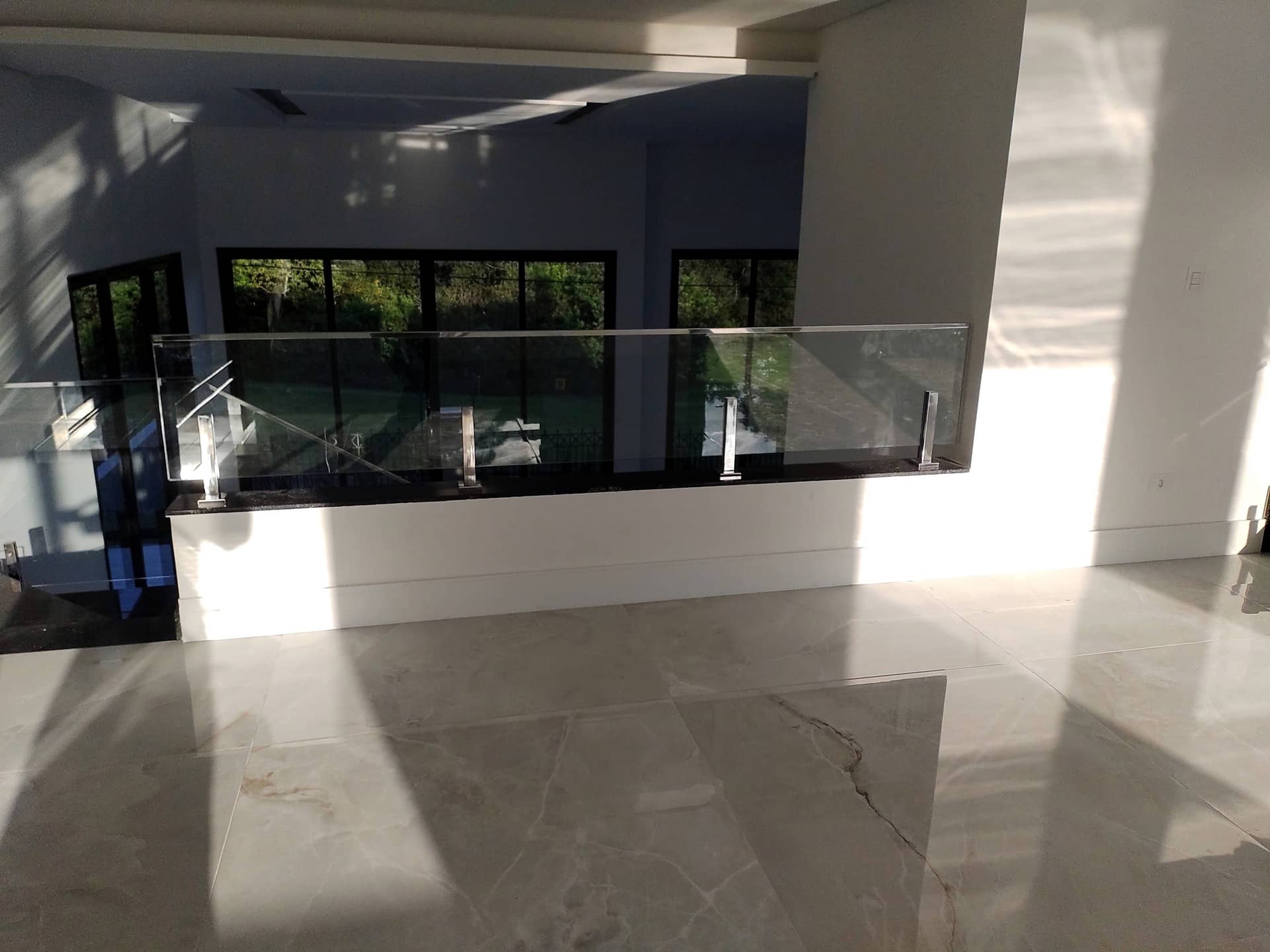 Guarda-corpo de vidro com colunas em inox no mezanino sobre piso de mármore