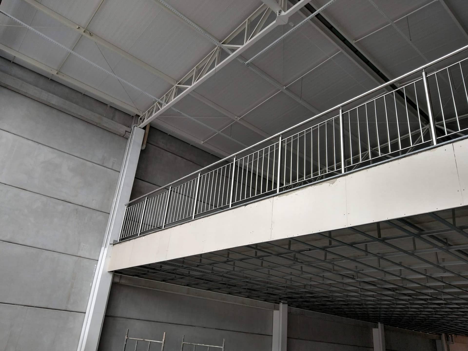 Mezanino de galpão com guarda-corpo de inox de travessas verticais ao longo de toda a borda