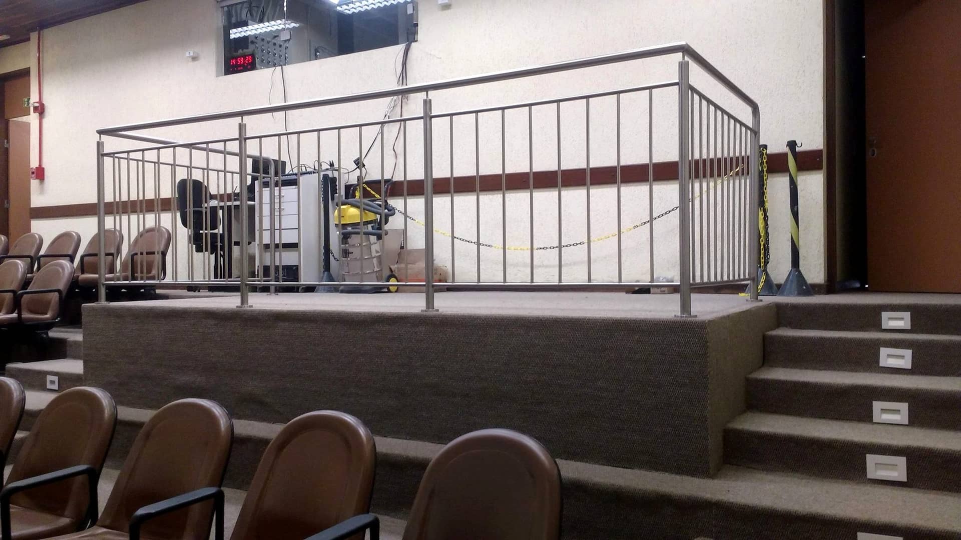 Palco de auditório com guarda-corpo de travessas verticais em inox e escada de acesso