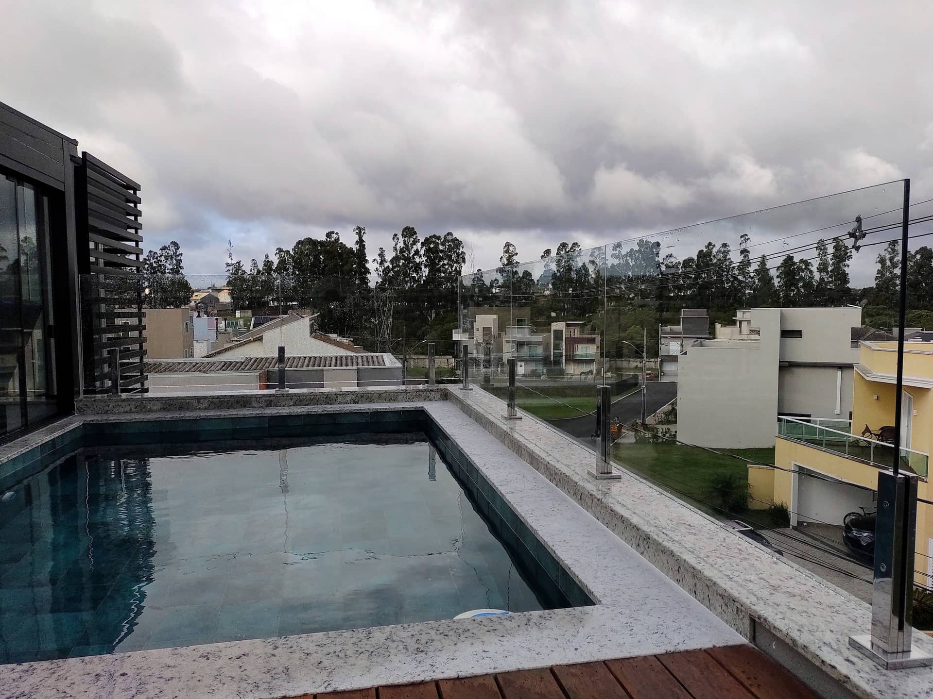 Borda da piscina da cobertura com o vidro acompanhando a lateral, com casas ao fundo
