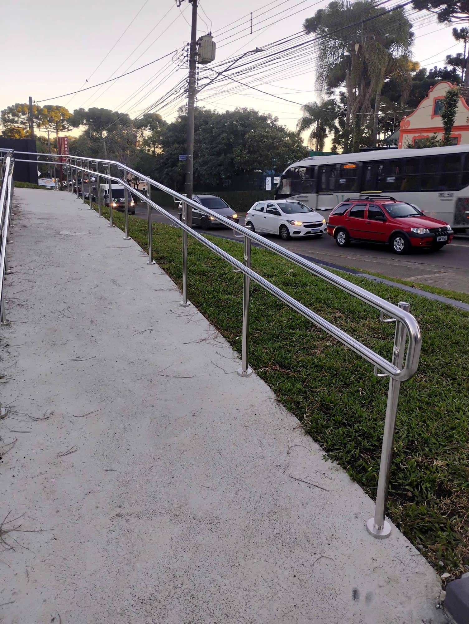 Rampa de acesso ao lado do gramado com corrimão em inox