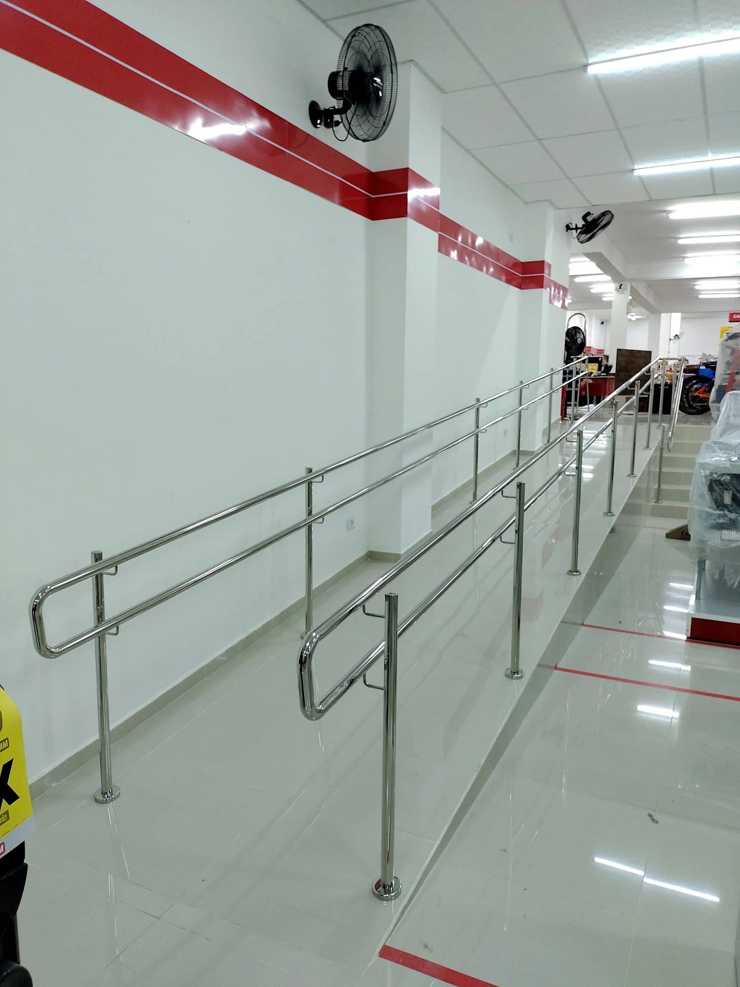 Corrimão duplo em inox ao longo da rampa da loja