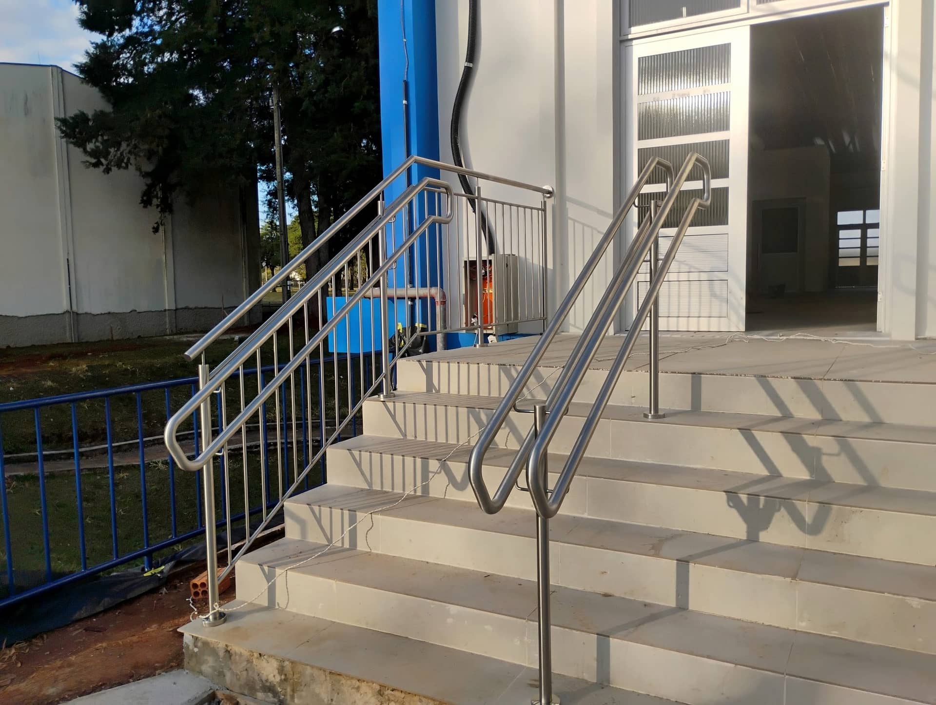 Escada de entrada com corrimão central e guarda-corpo em inox