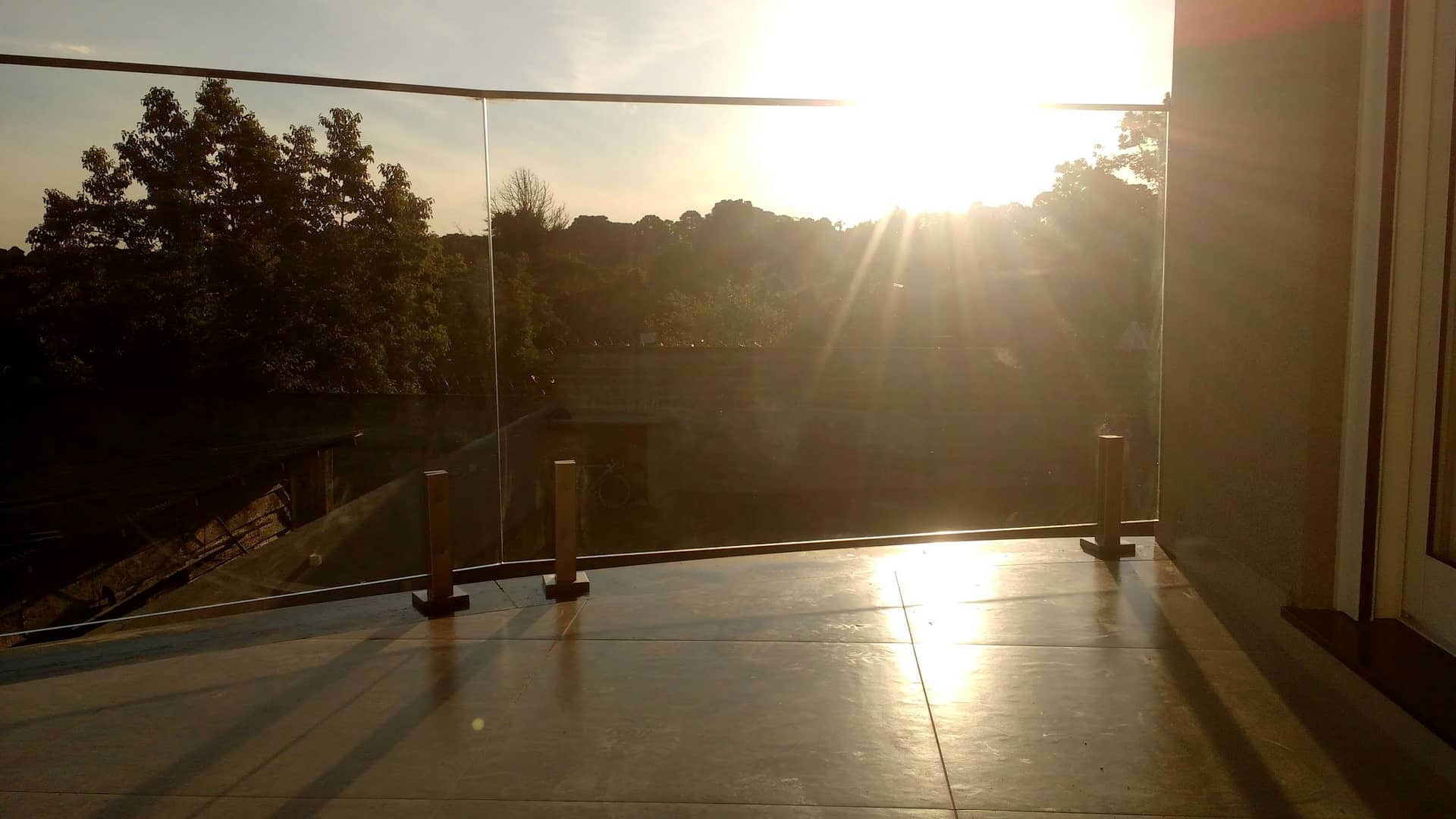 Terraço com guarda-corpo de vidro contra o pôr do sol