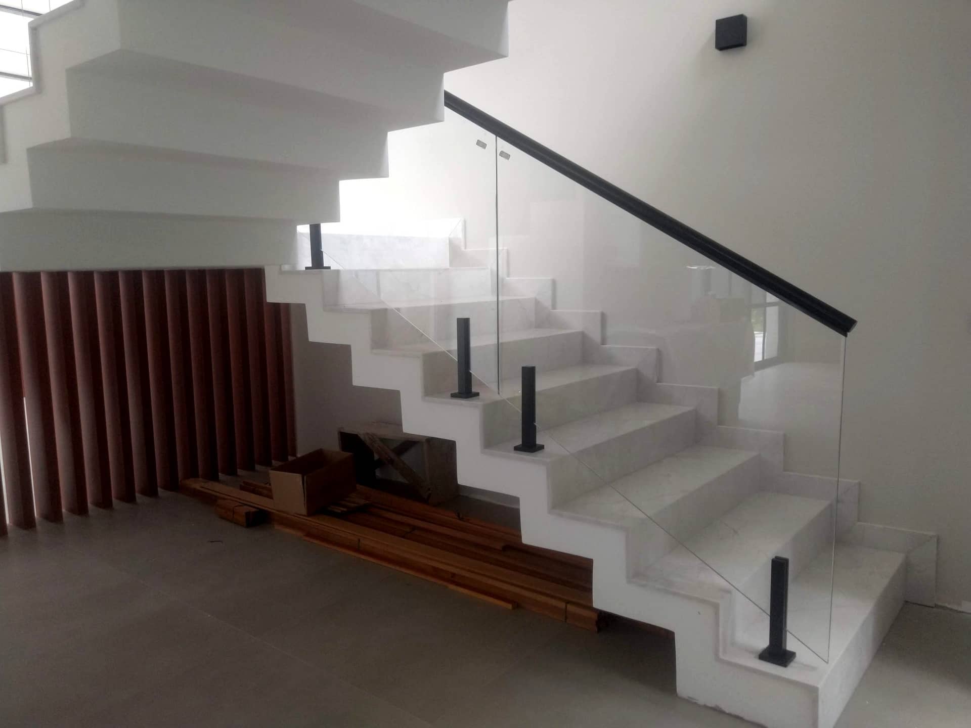 Escada branca com guarda-corpo de vidro e corrimão preto