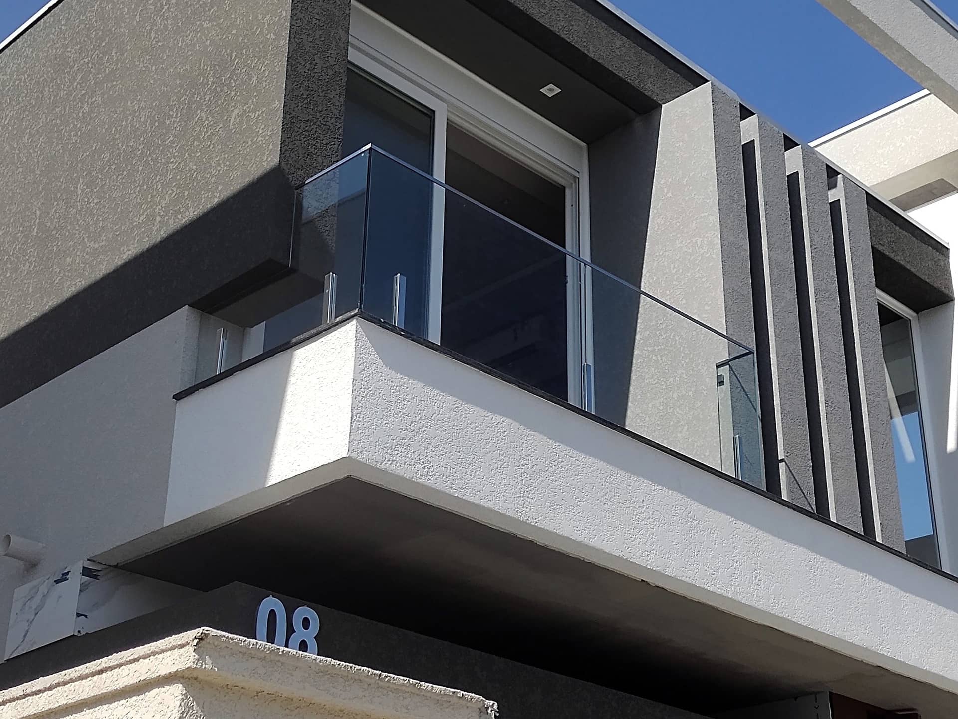 Sacada com guarda-corpo de vidro e colunas em inox