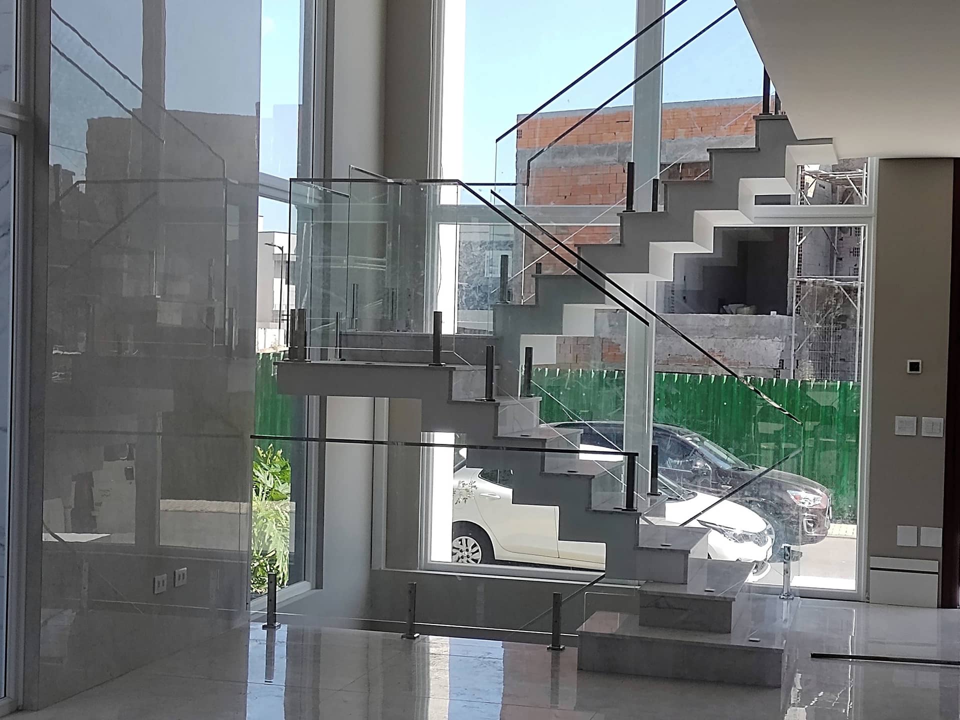 Escada interna com vidro em frente à janela de pé-direito duplo