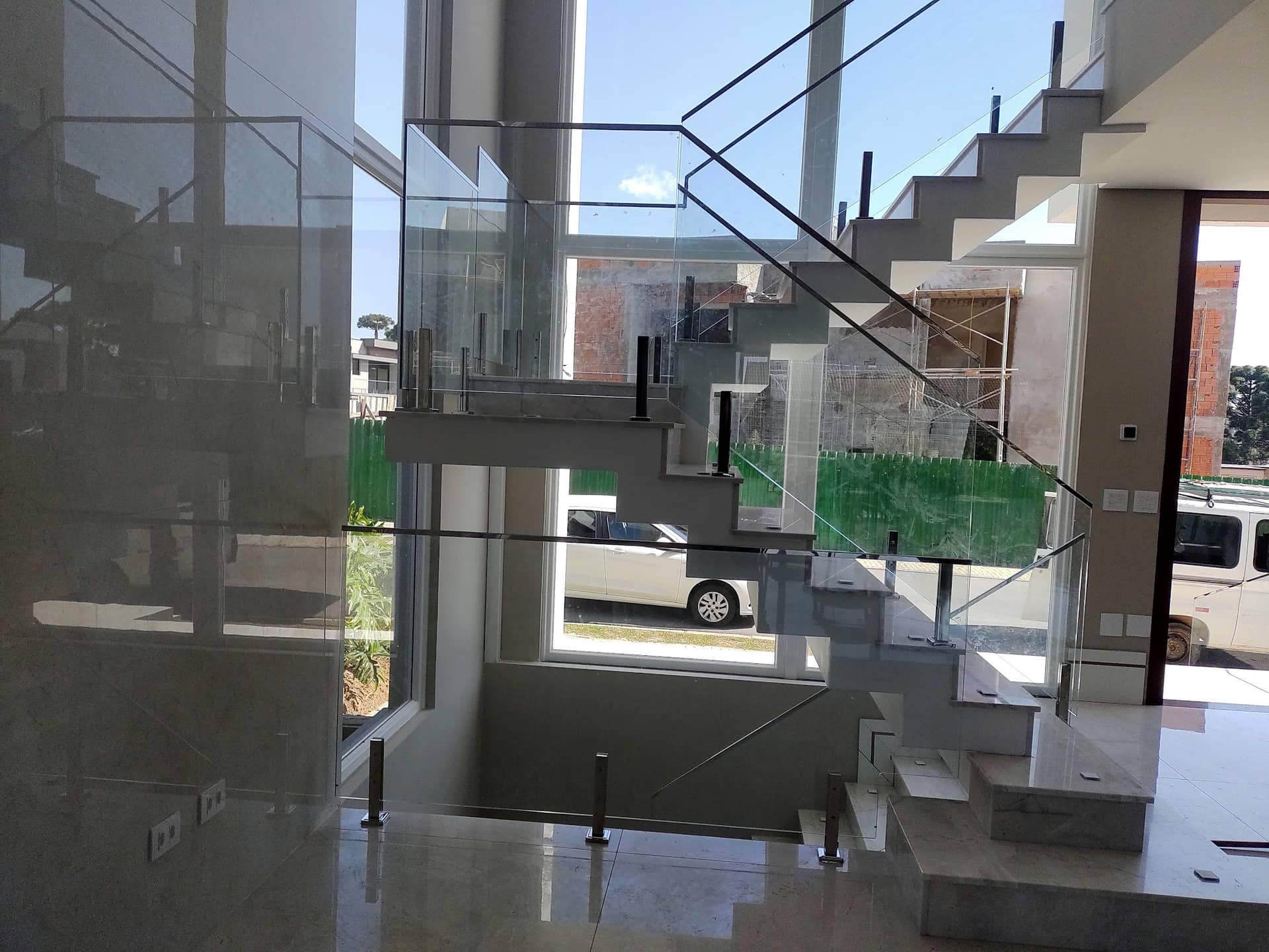 Escada e guarda-corpo de vidro vistos através da fachada envidraçada