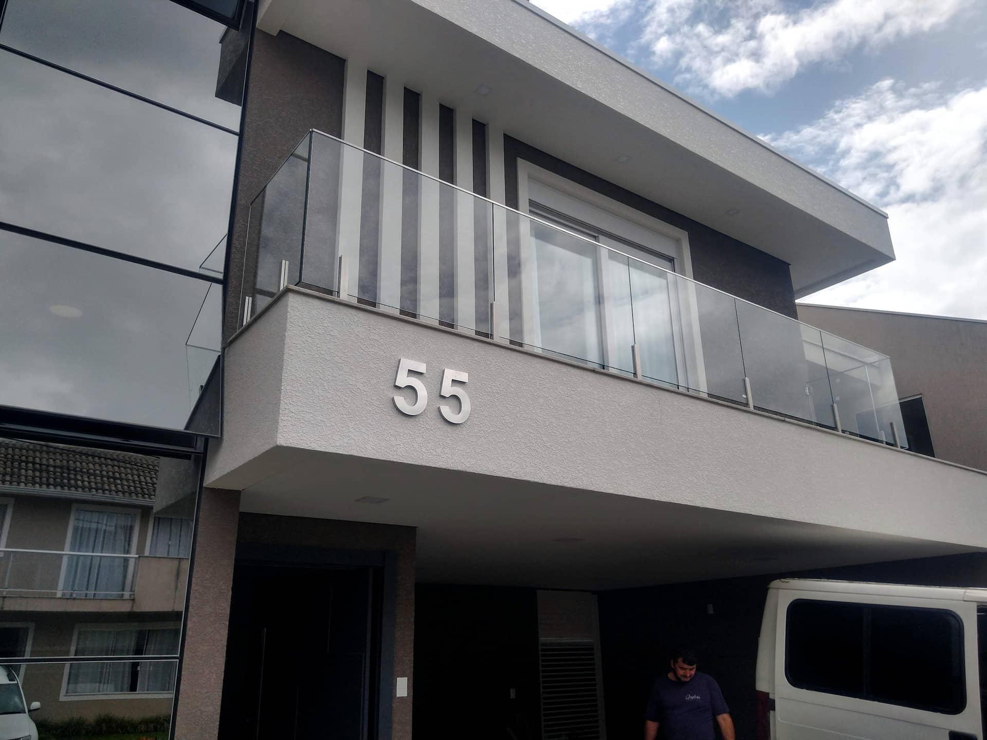 Sacada com guarda-corpo de vidro e brises verticais na fachada