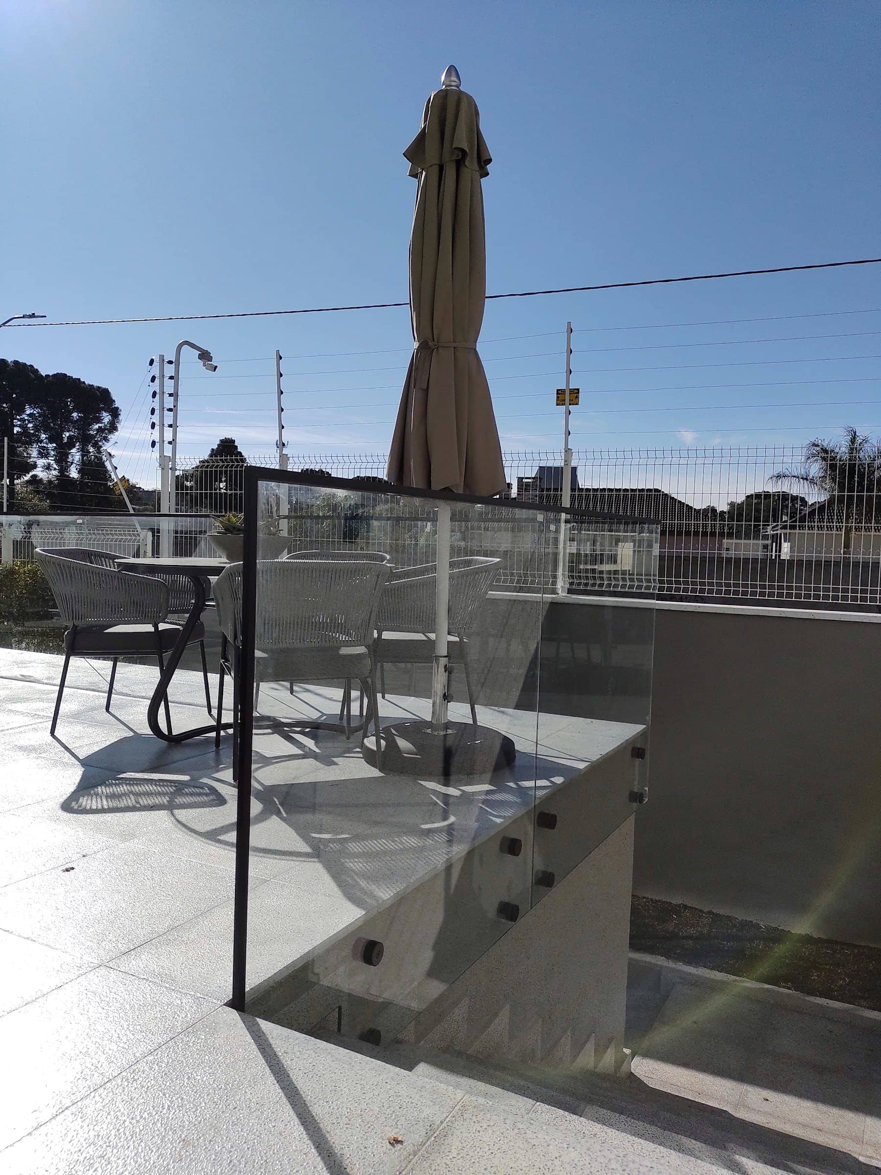 Canto do guarda-corpo de vidro no terraço, com fixação lateral em inox