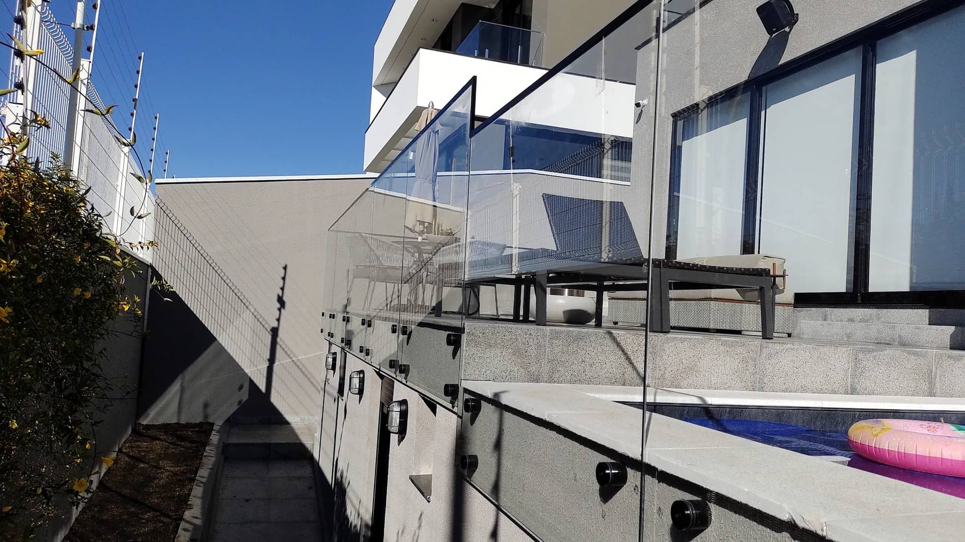 Lateral do terraço com o guarda-corpo de vidro e a piscina vistos de fora