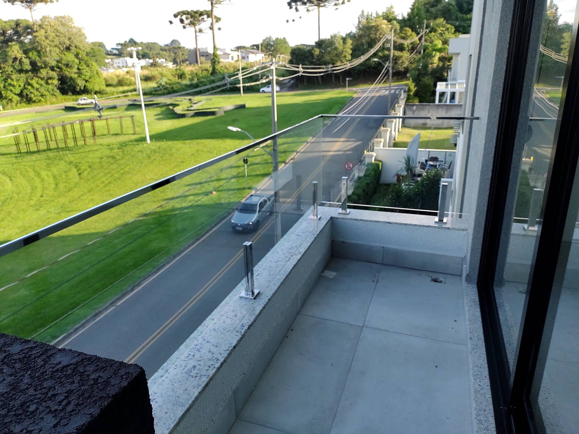 Guarda-corpo de vidro de varanda com vista para gramado e rua