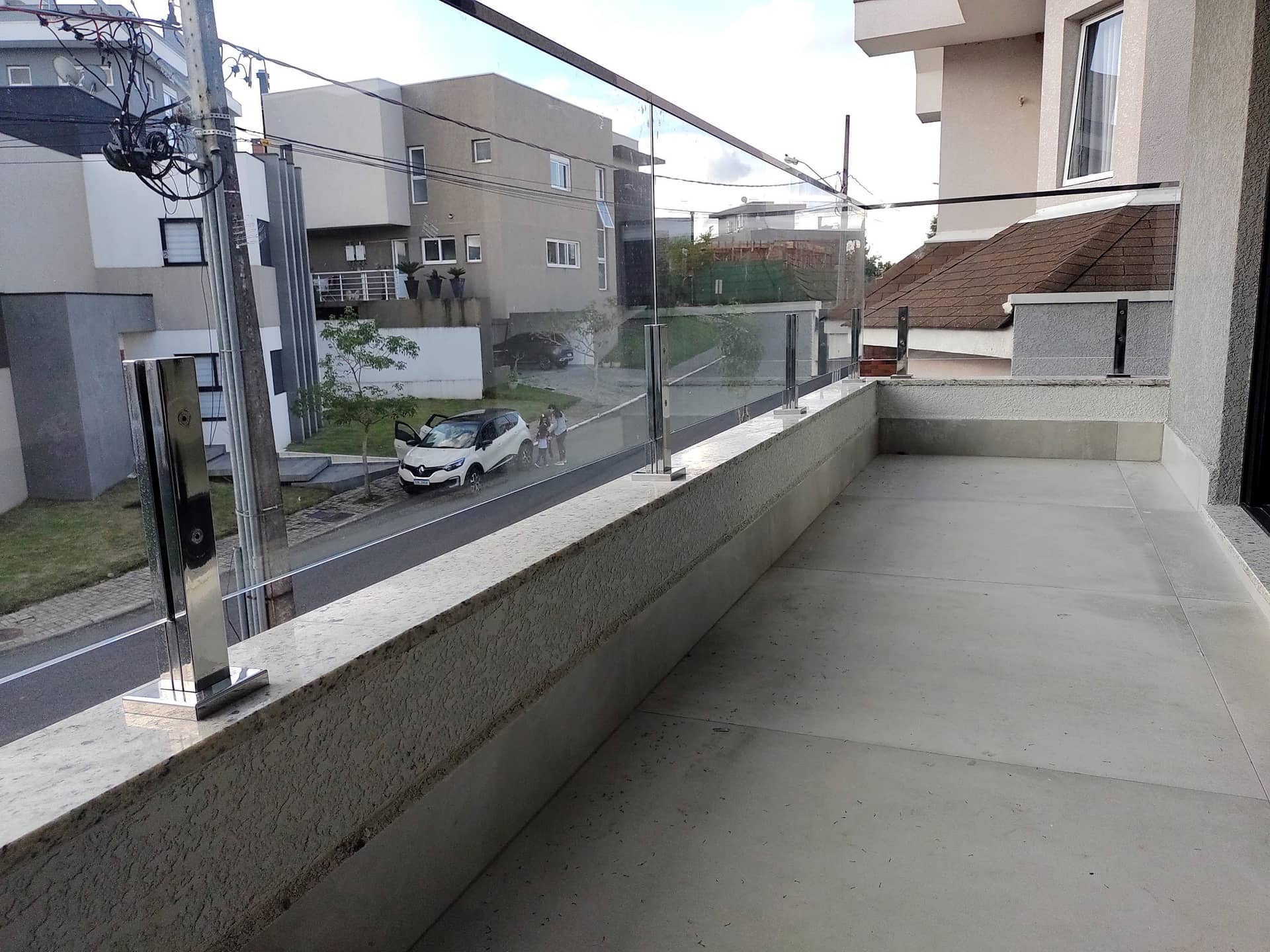 Varanda lateral com guarda-corpo de vidro acompanhando a fachada