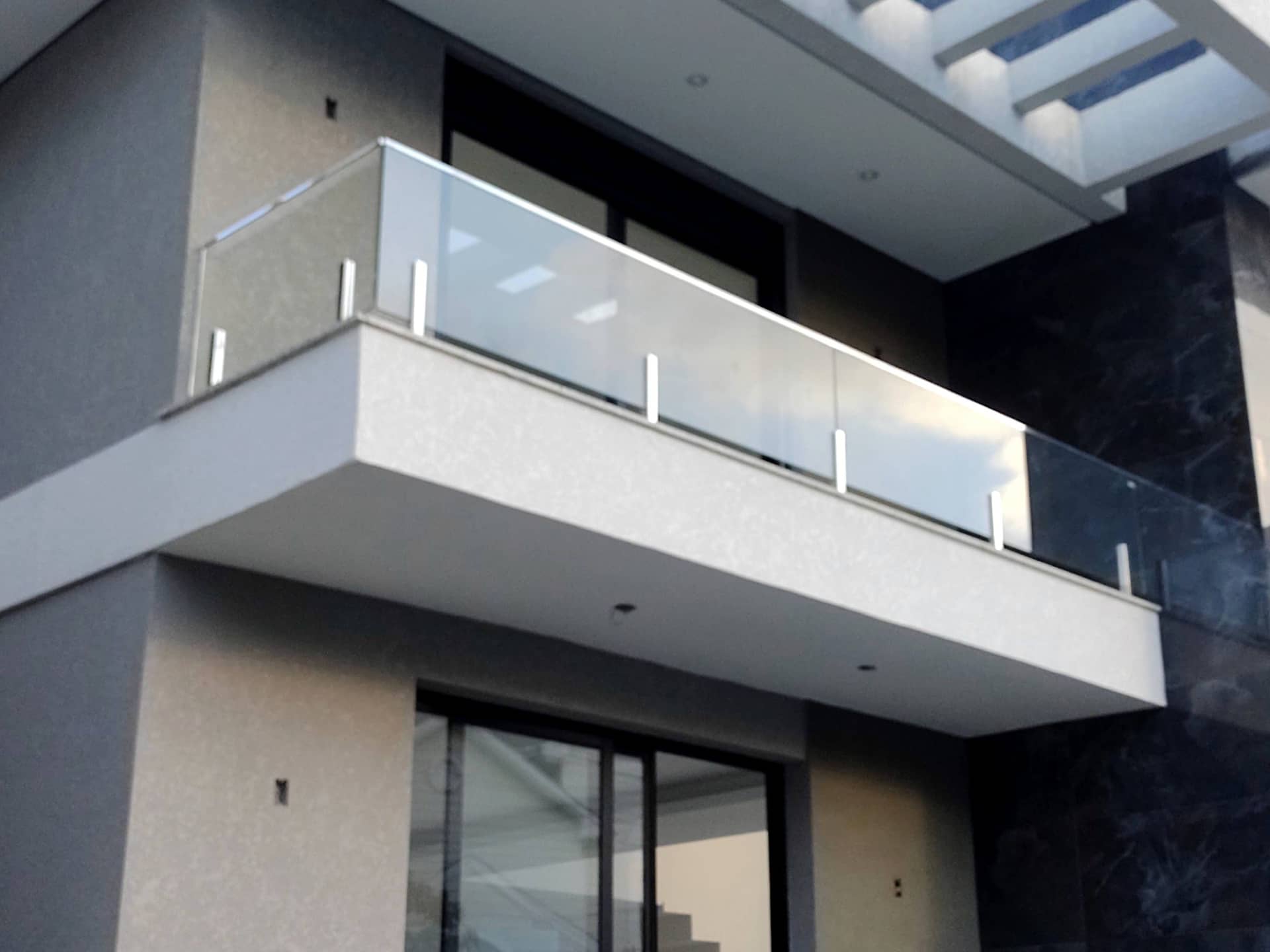 Sacada em balanço com guarda-corpo de vidro e colunas em inox