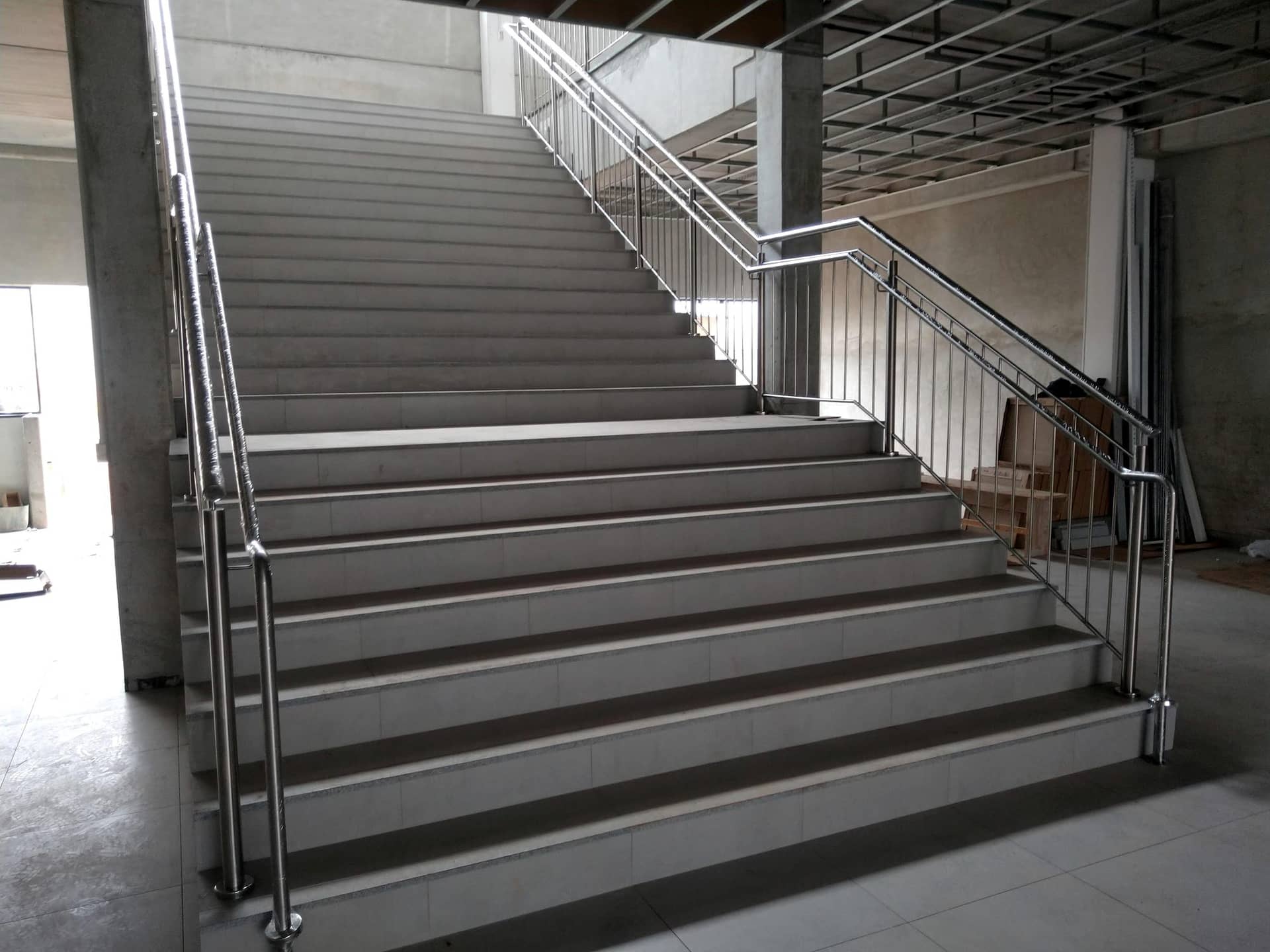 Escadaria com corrimãos em inox nas laterais e no centro