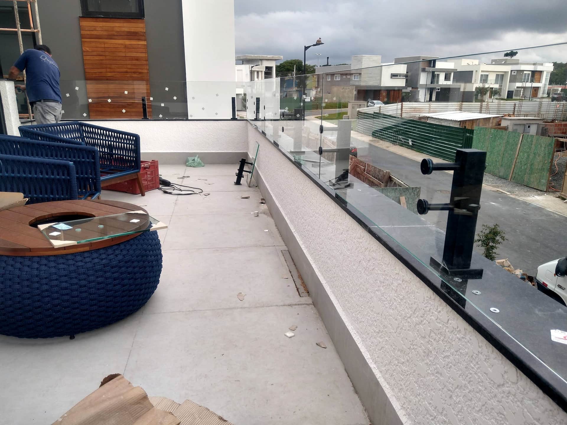 Instalação de guarda-corpo de vidro com fixação lateral em terraço, com a obra em andamento