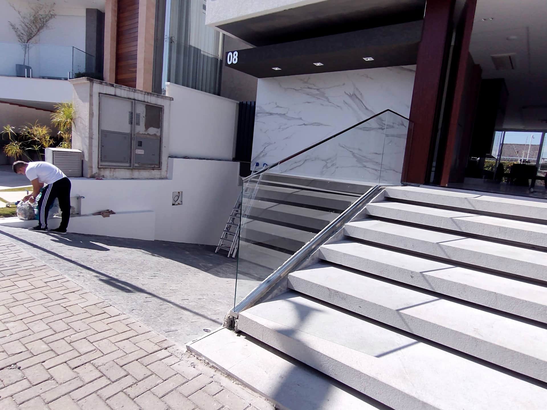 Trabalho na escadaria de entrada com guarda-corpo de vidro e corrimão em inox